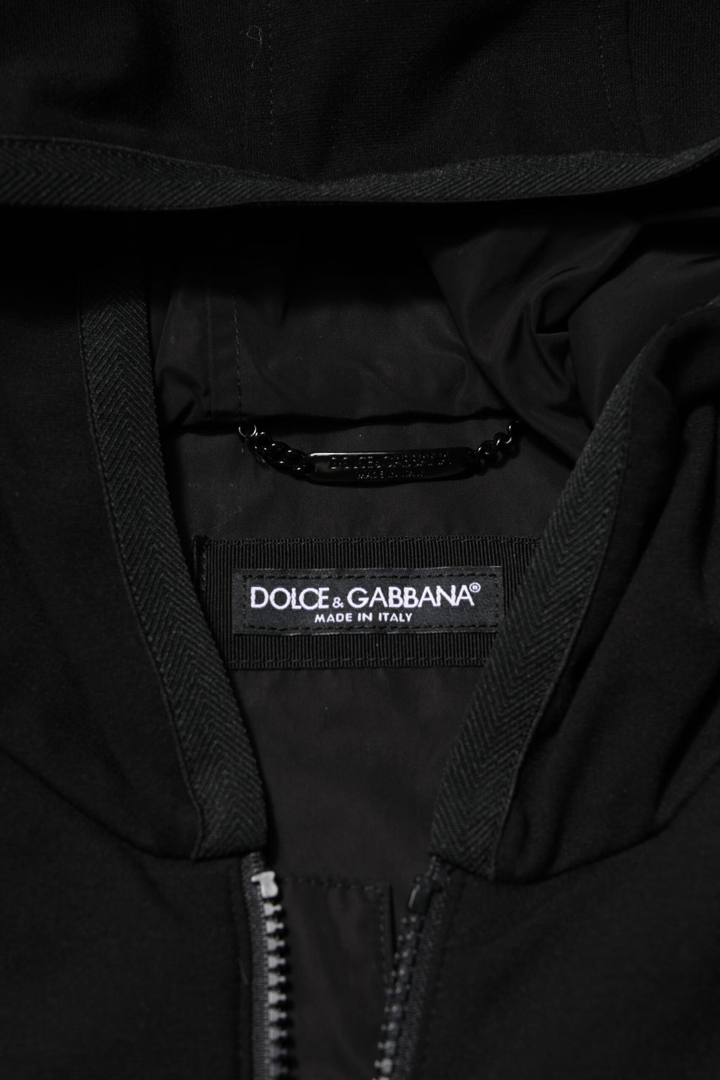 Veste sans manches Dolce & Gabbana noire avec capuche, logo et plaque sur le devant, en tissu élégant et moderne.
