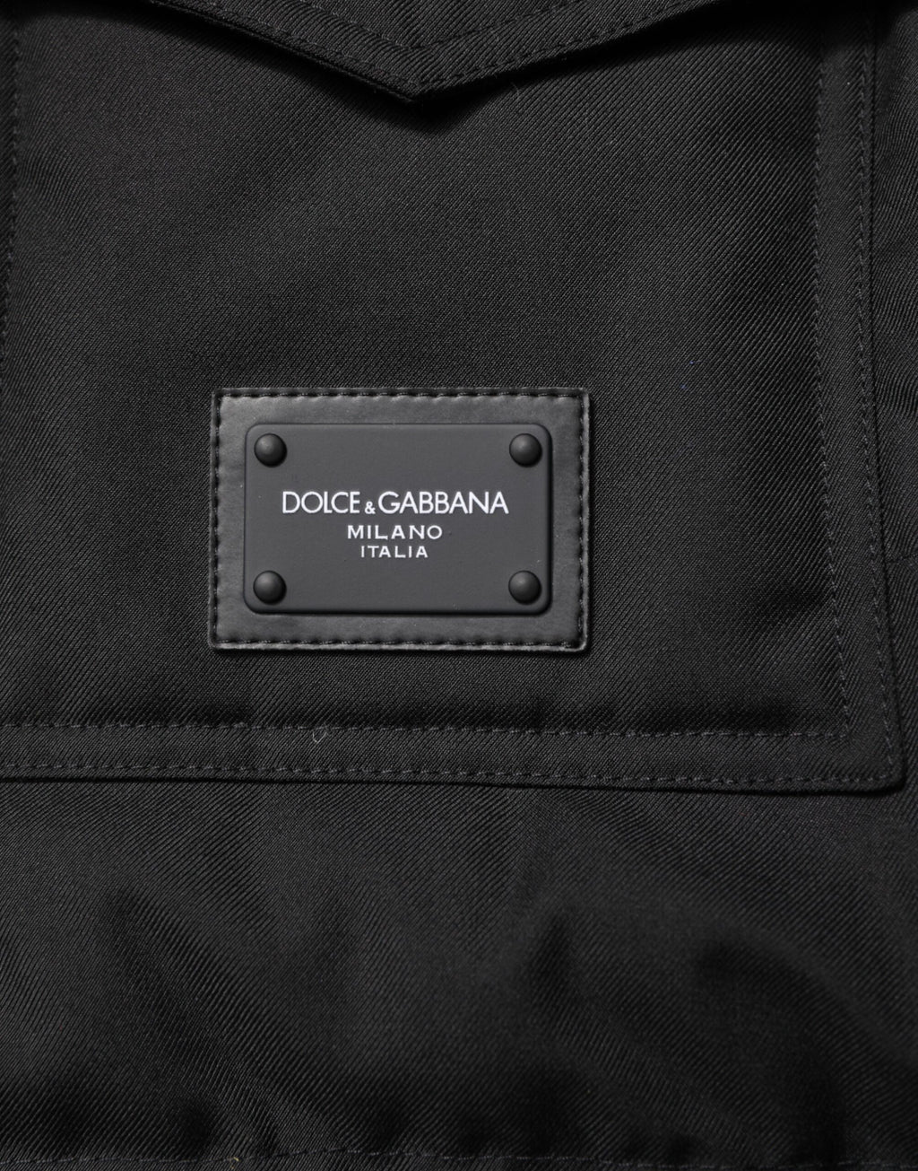 Veste sans manches Dolce & Gabbana noire avec plaque logo, parka élégante et moderne, visible en détail sur l'image.