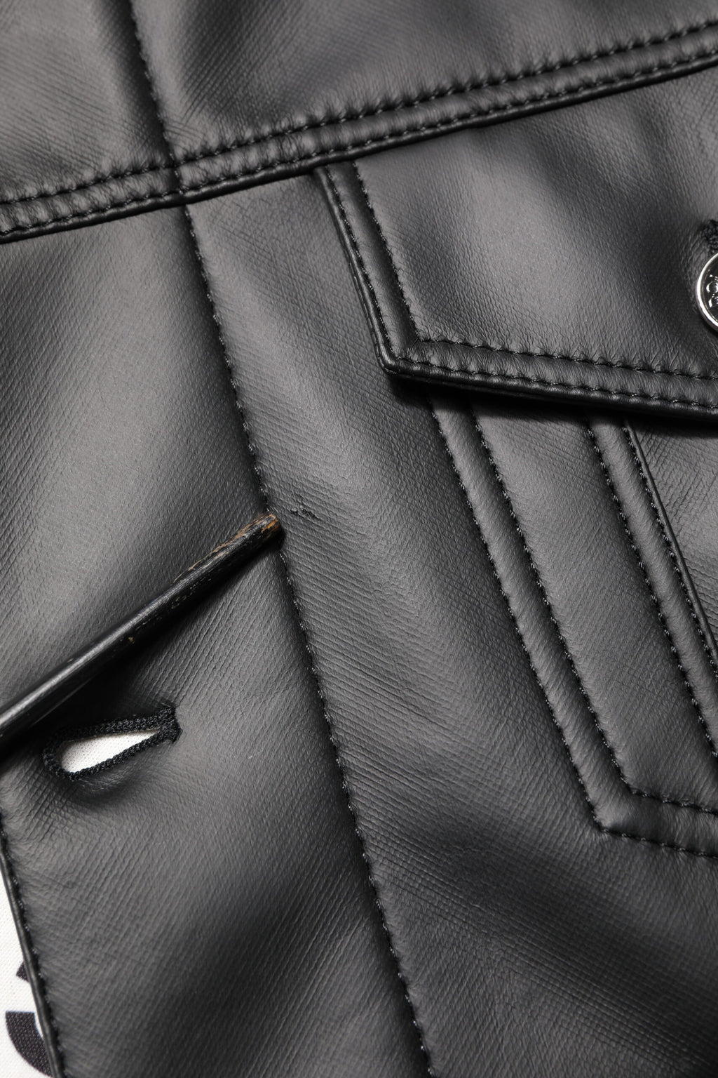 Veste en polyester noire Dolce & Gabbana avec boutons, style biker, vue de face sur une texture en cuir synthétique.