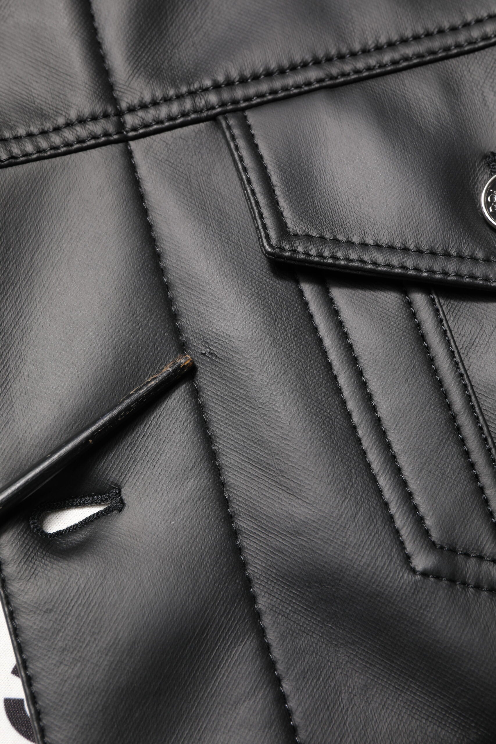 Veste en polyester noire Dolce & Gabbana avec boutons, style biker, vue de face sur une texture en cuir synthétique.