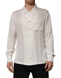 Chemise en soie blanche Dolce & Gabbana avec logo DG imprimé, manches longues et design élégant visible sur l’image.