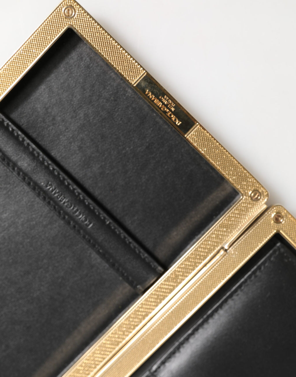 Pochette en cuir noir Dolce & Gabbana avec cadre doré, idéale pour soirée et événements élégants.