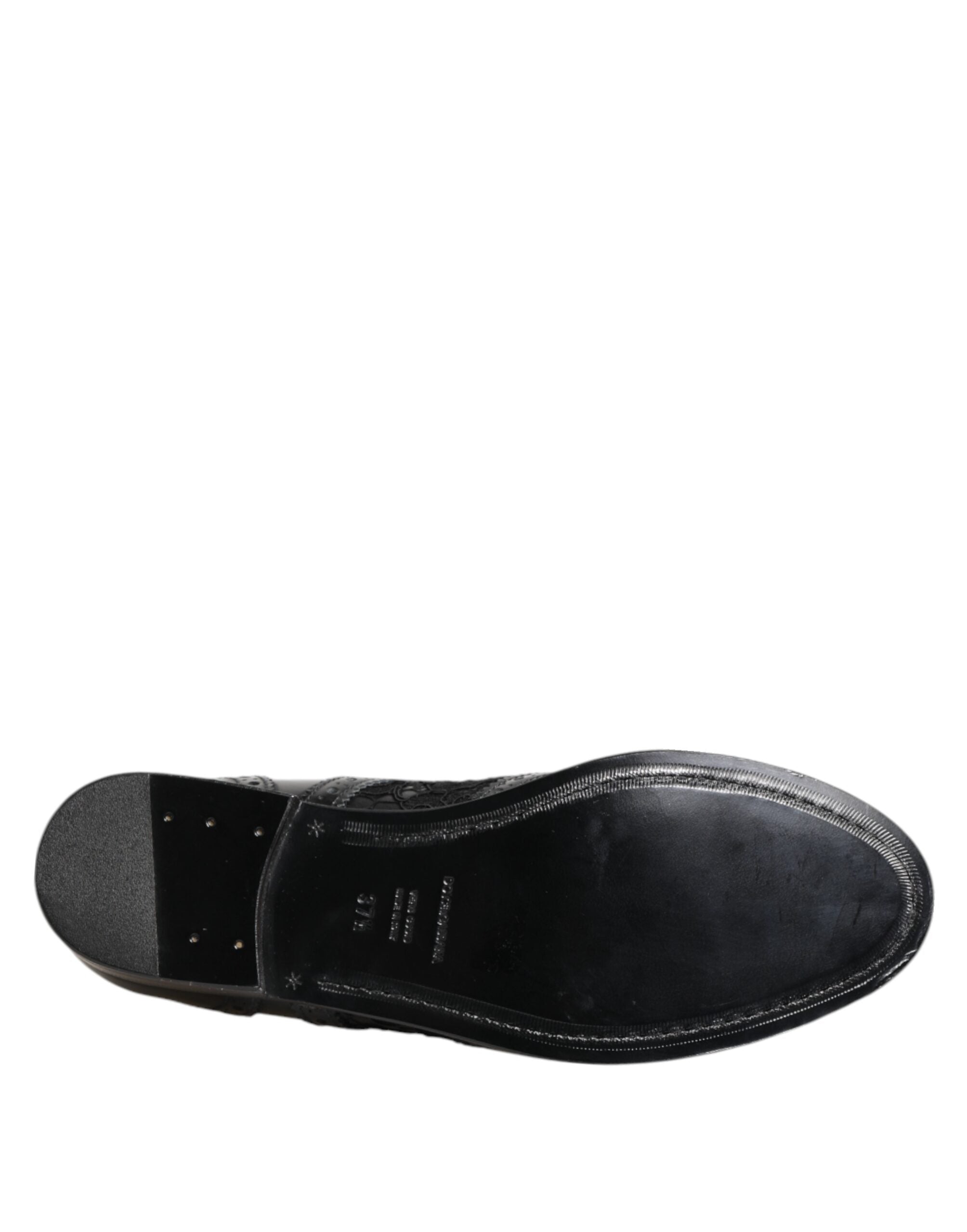 Robe noire en cuir avec broderies florales et chaussures formelles Dolce & Gabbana sur fond neutre.