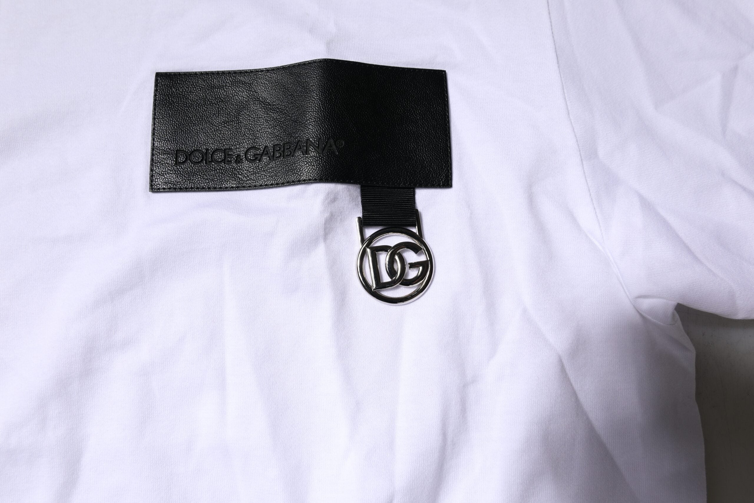 T-shirt blanc Dolce & Gabbana avec logo, col rond, manches courtes et design élégant, porté sur mannequin.