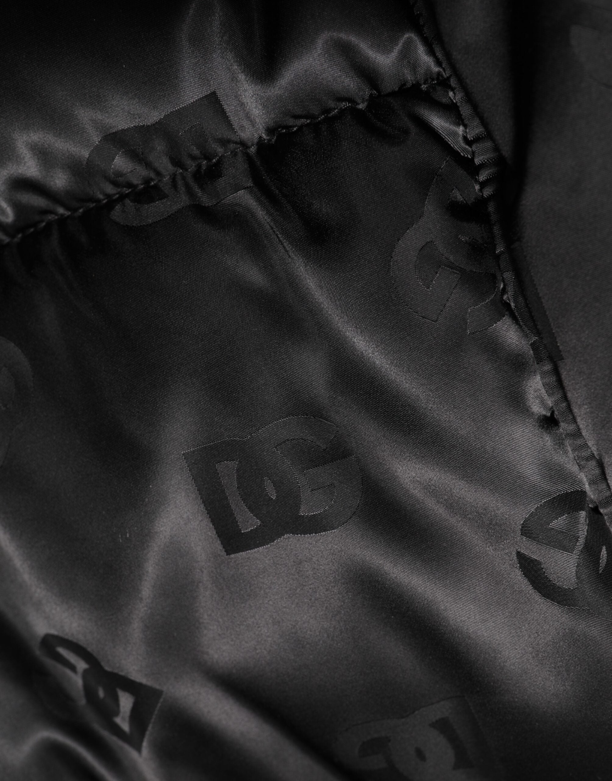 Veste matelassée noire Dolce & Gabbana avec logo monogramme, capuche en nylon, style puffer.