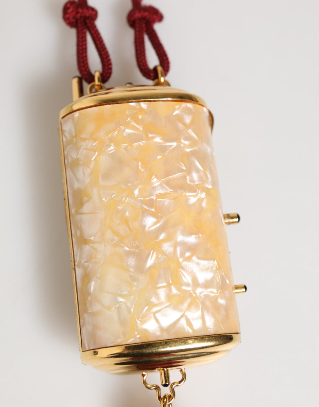 Sac Dolce & Gabbana blanc en résine perles avec pendentif en métal doré et tresse rouge, style élégant et sophistiqué.