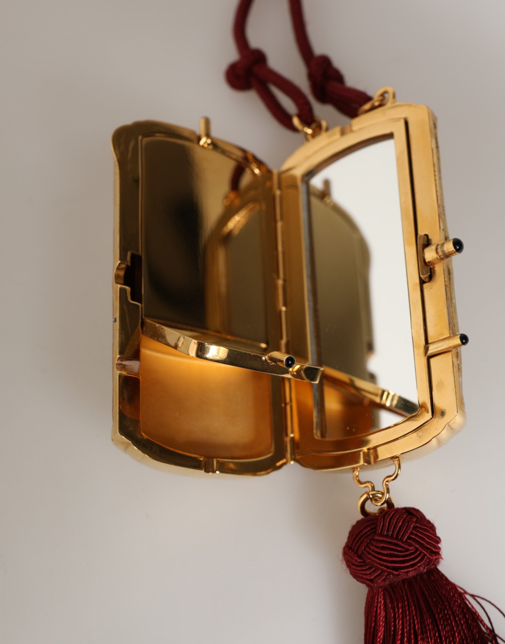 Sac Dolce & Gabbana blanc en résine perle avec pendentif en métal doré, ruban rouge et pompon en tassel rouge.