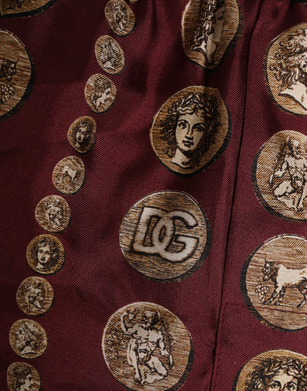 Boxers de bain homme Dolce & Gabbana en soie bordeaux avec motif pièces de monnaie, coupe courte et élégante.