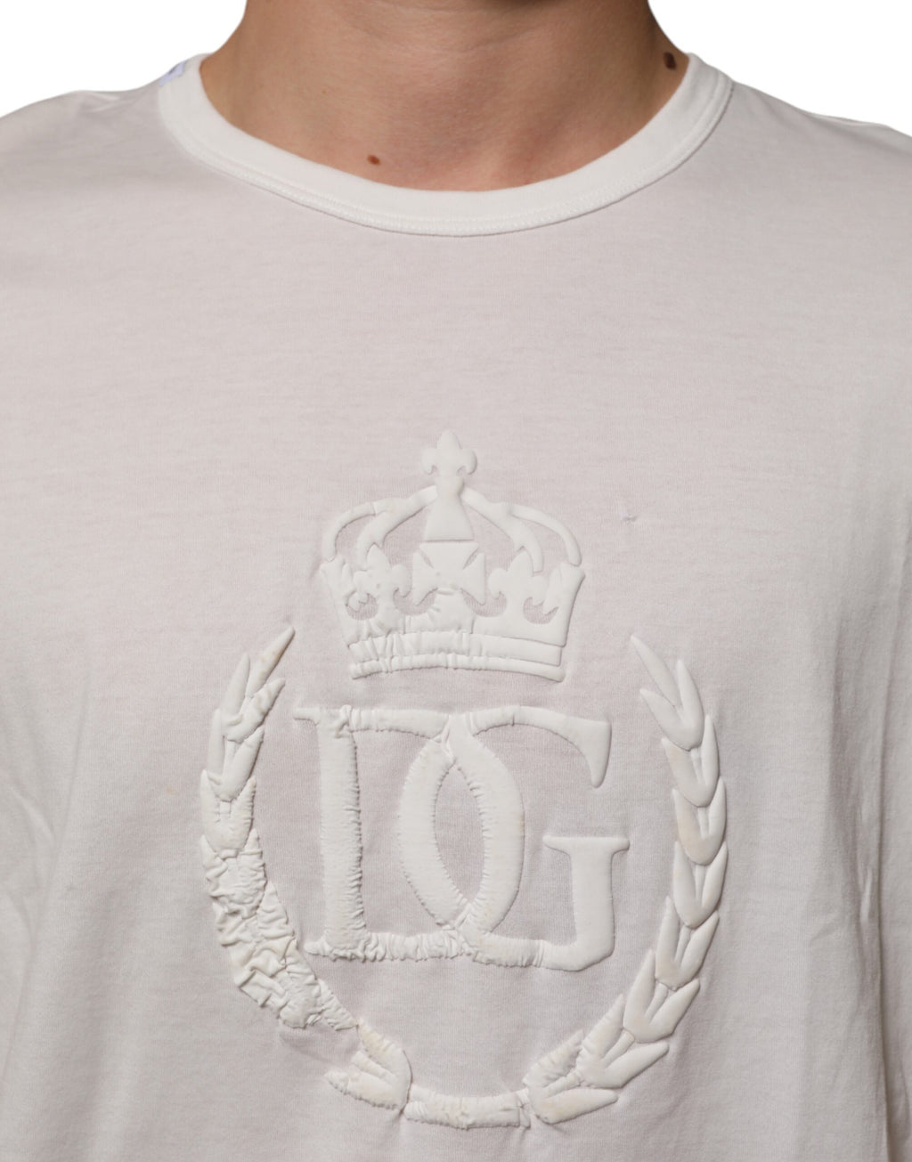 T-shirt blanc en coton Dolce & Gabbana avec embossage de la couronne DG, porté par un homme.