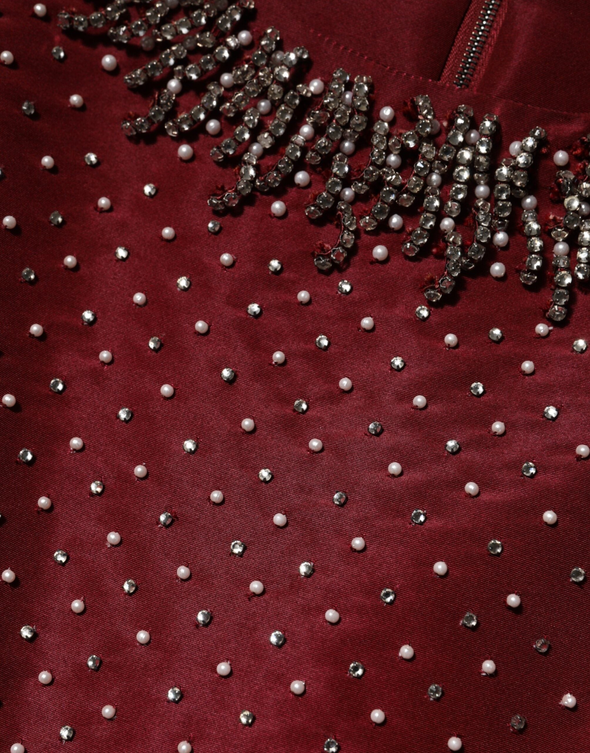 Robe de soirée en soie bordeaux avec perles, conçue par Dolce & Gabbana, élégante et ornée de détails sophistiqués.