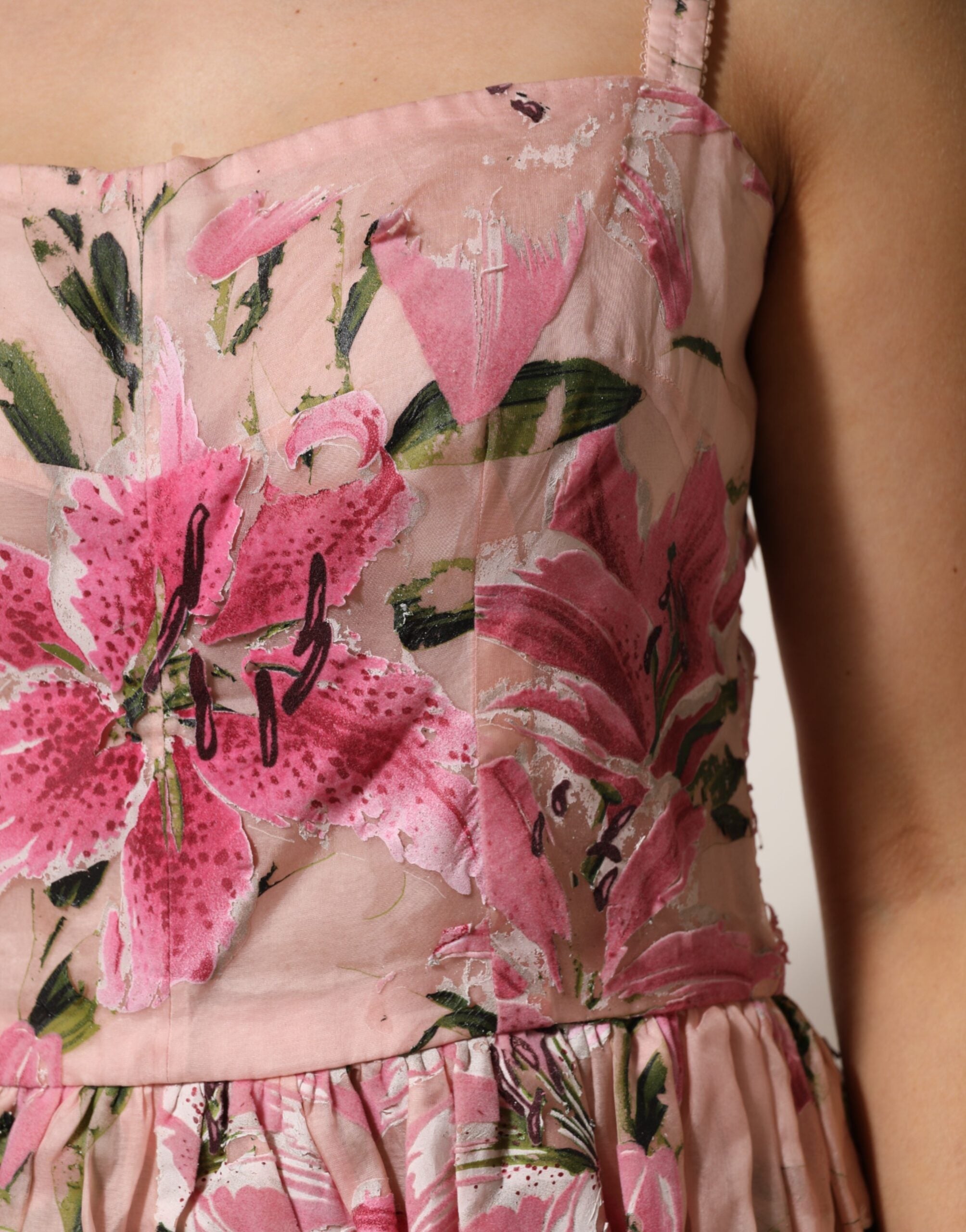 Robe sans manches en coton rose à fleurs et plis de Dolce & Gabbana, élégante et estivale, portée par une femme.