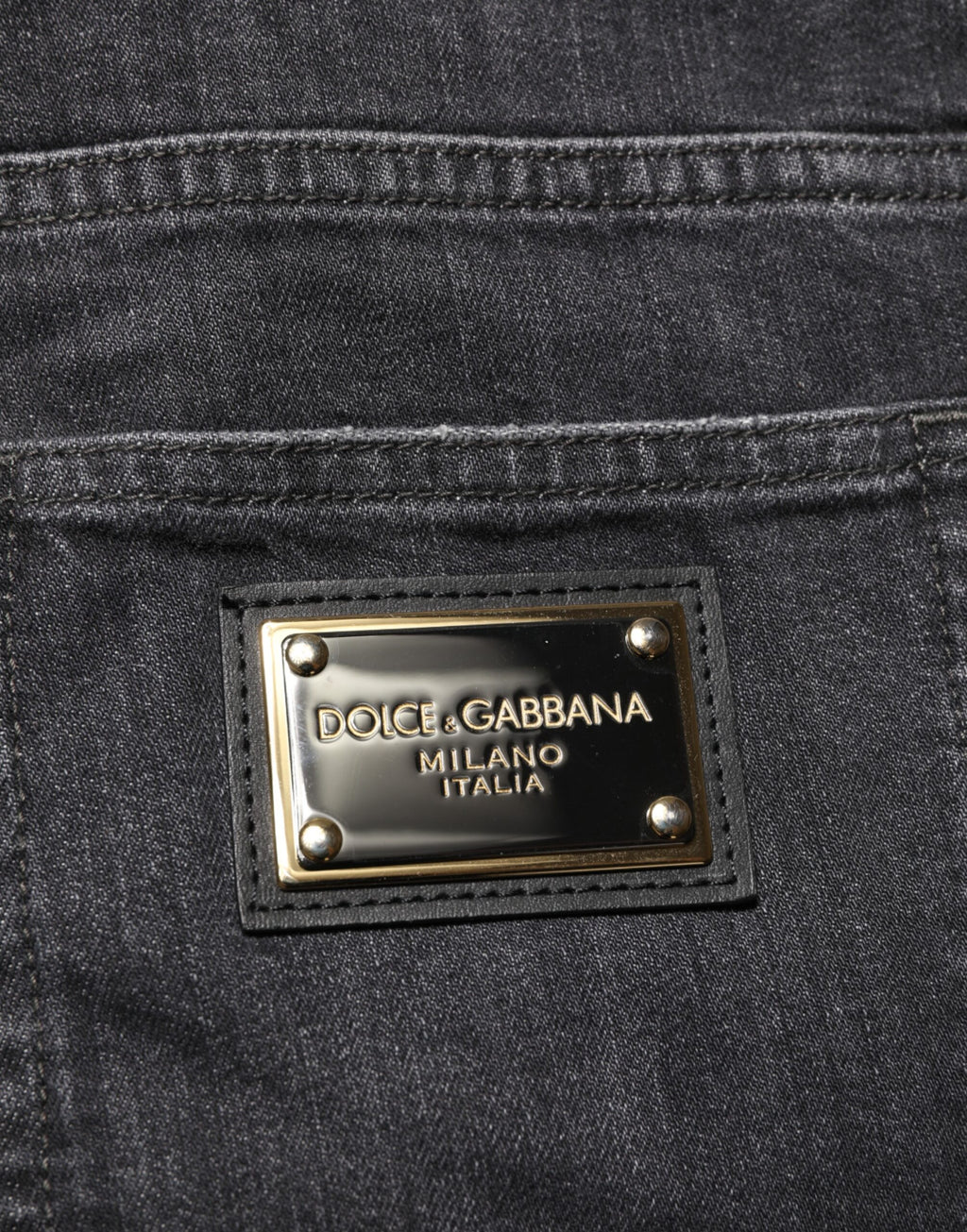 Jeans noirs Dolce & Gabbana en coton slim fit avec déchirures, détails usés et logo visible.