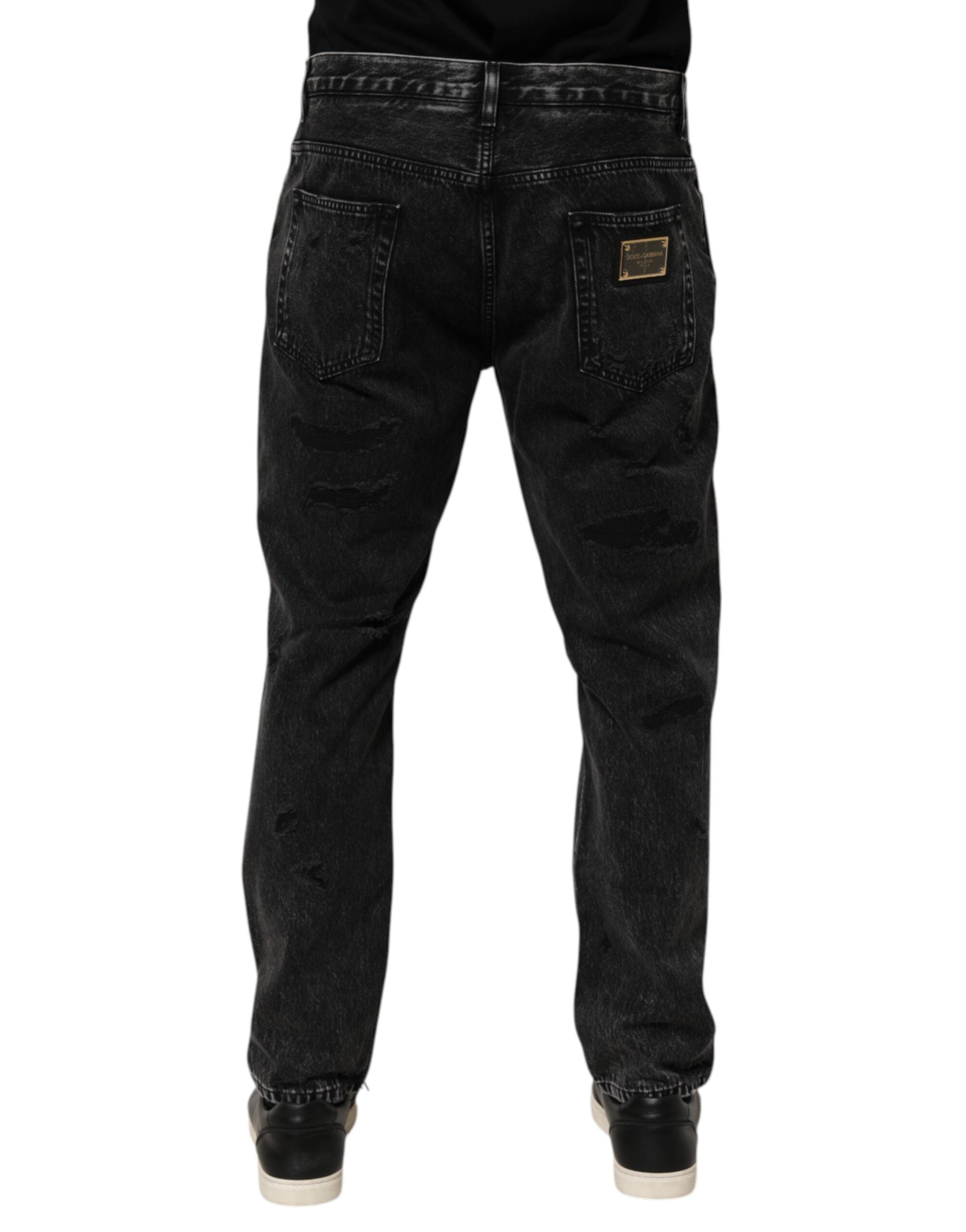 Jeans en denim coton délavé noir Dolce & Gabbana avec déchirures et coupe lâche, visible en gros plan.