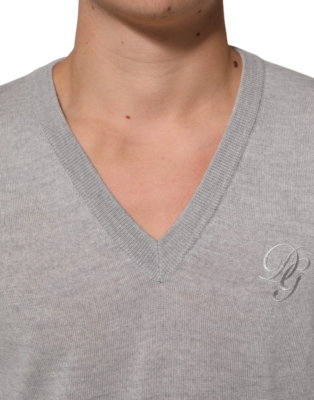 Pull à col en V en laine gris Dolce & Gabbana avec logo, style confortable et élégant, porté sur un mannequin.