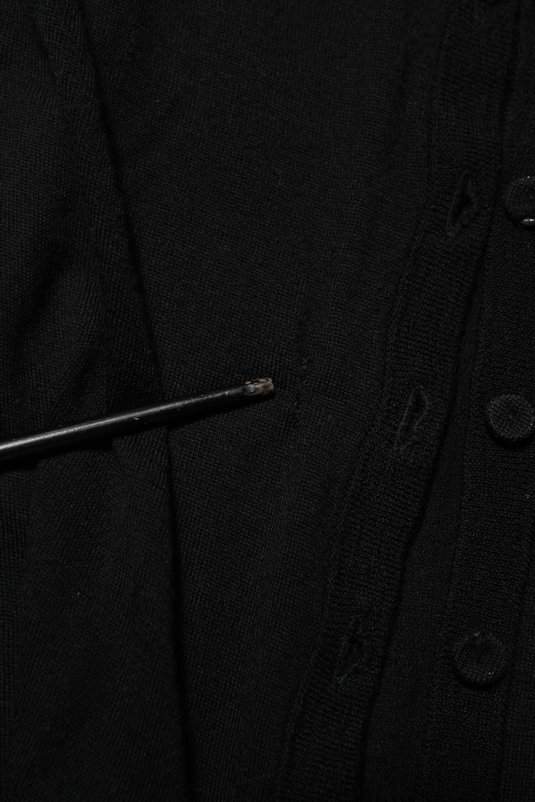 Cardigan noir en laine vierge Dolce & Gabbana avec boutons, porté sur un mannequin, détails du tricot et coupe élégante.