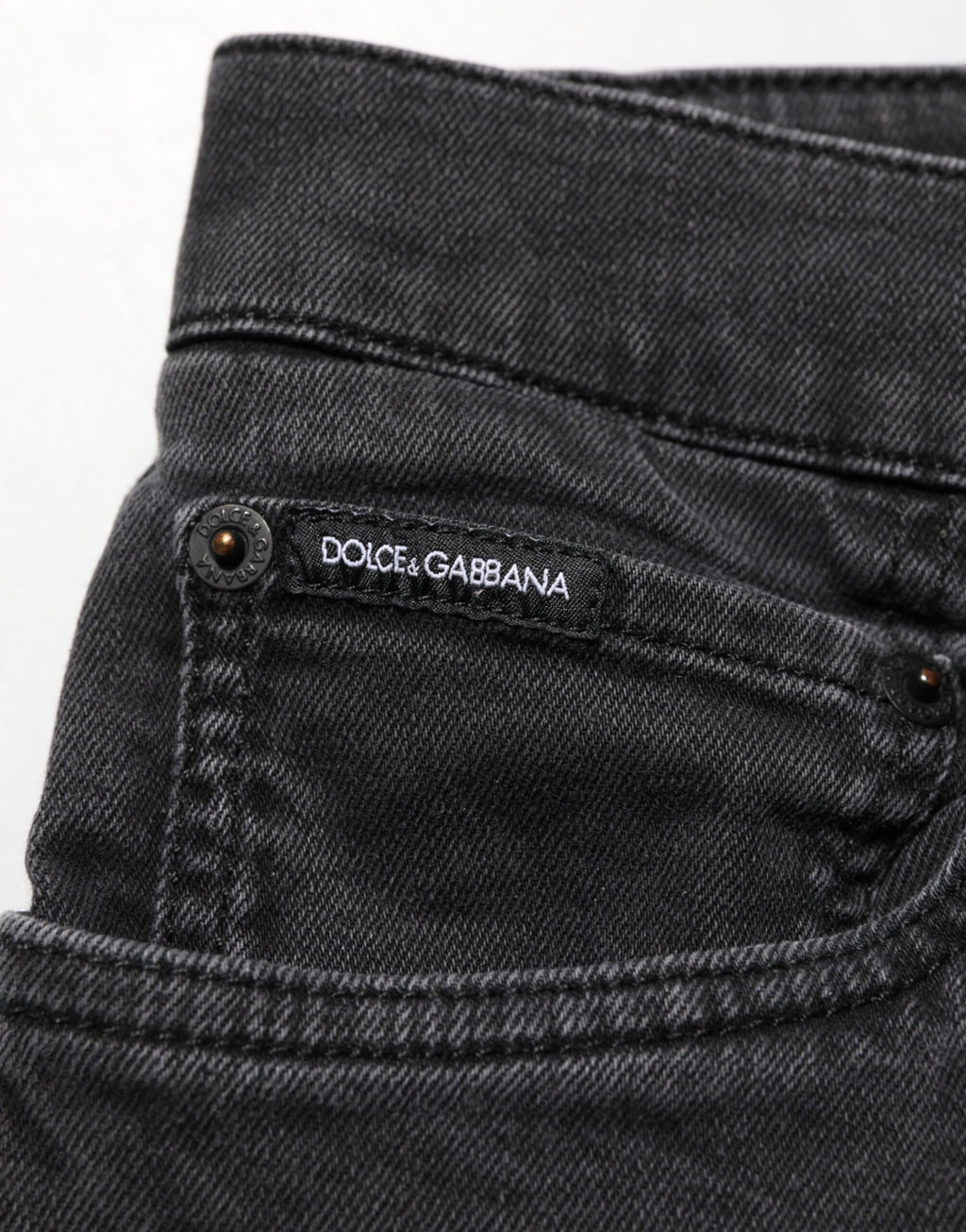 Jeans Dolce & Gabbana en denim gris foncé, coupe slim en coton stretch, visible sur un mannequin avec poches et fermeture éclair.