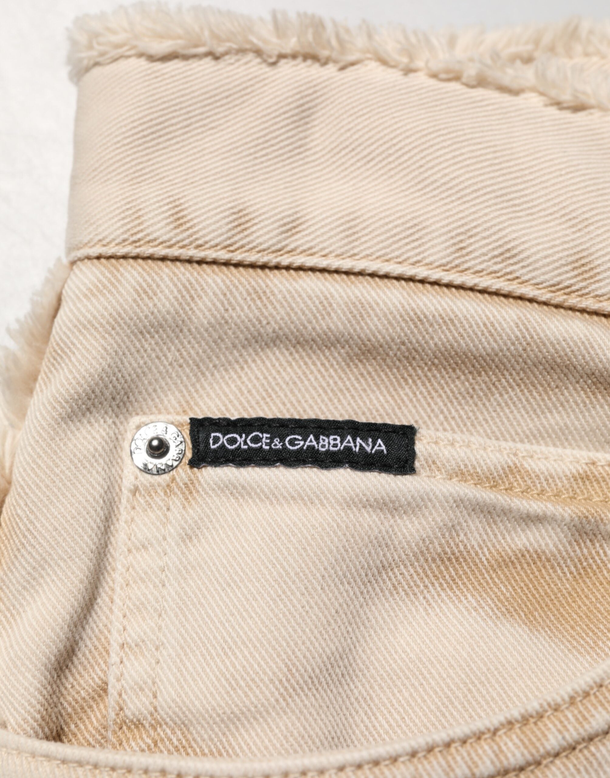 Pantalon en denim beige Dolce & Gabbana en coton, coupe droite, style jean, visible boutons et poches avant.