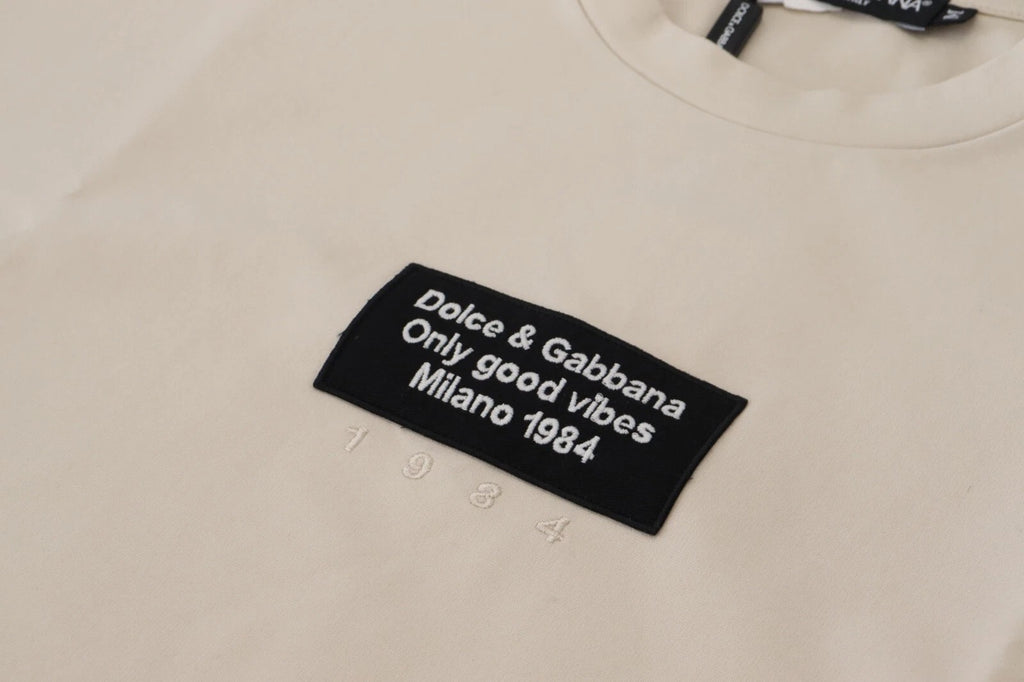 Pull Dolce & Gabbana en coton ivoire avec imprimé, col rond, visible sur fond neutre dans l'image.