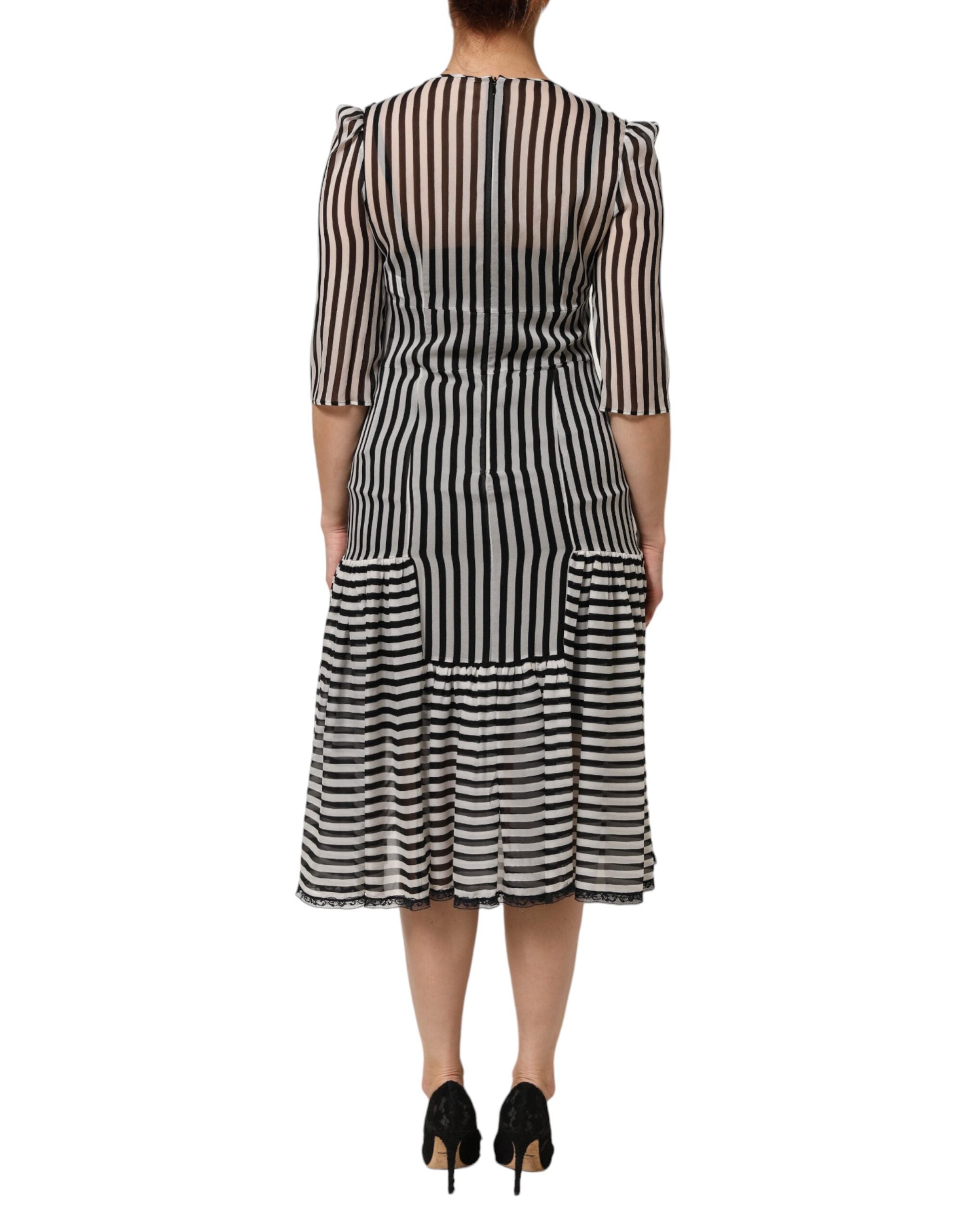 Robe midi en soie noire et blanche à rayures avec décolleté en V de la marque Dolce & Gabbana, visible sur l'image.