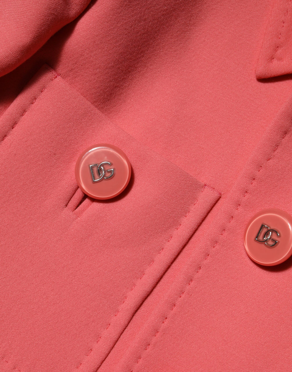 Manteau trench rose Dolce & Gabbana à boutons, long et élégant, porté sur un modèle.