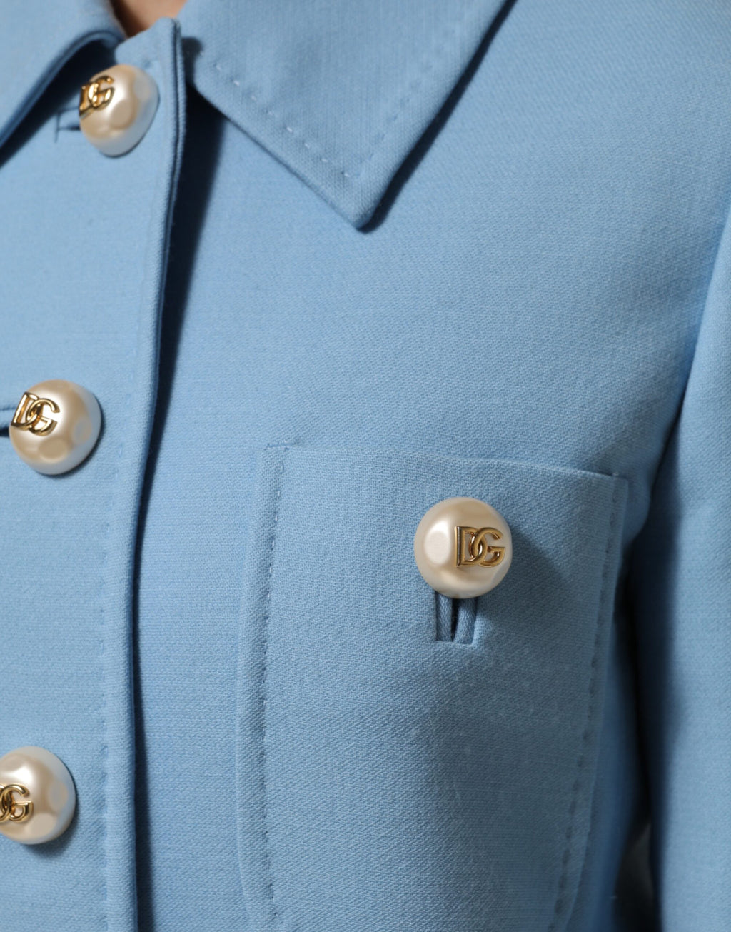 Manteau trench bleu Dolce & Gabbana à boutons, classique et élégant, porté sur un modèle, vue en détail.