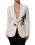 Veste beige Dolce & Gabbana à boutons, broderie élégante, coupe simple et raffinée, visible en gros plan sur l'image.
