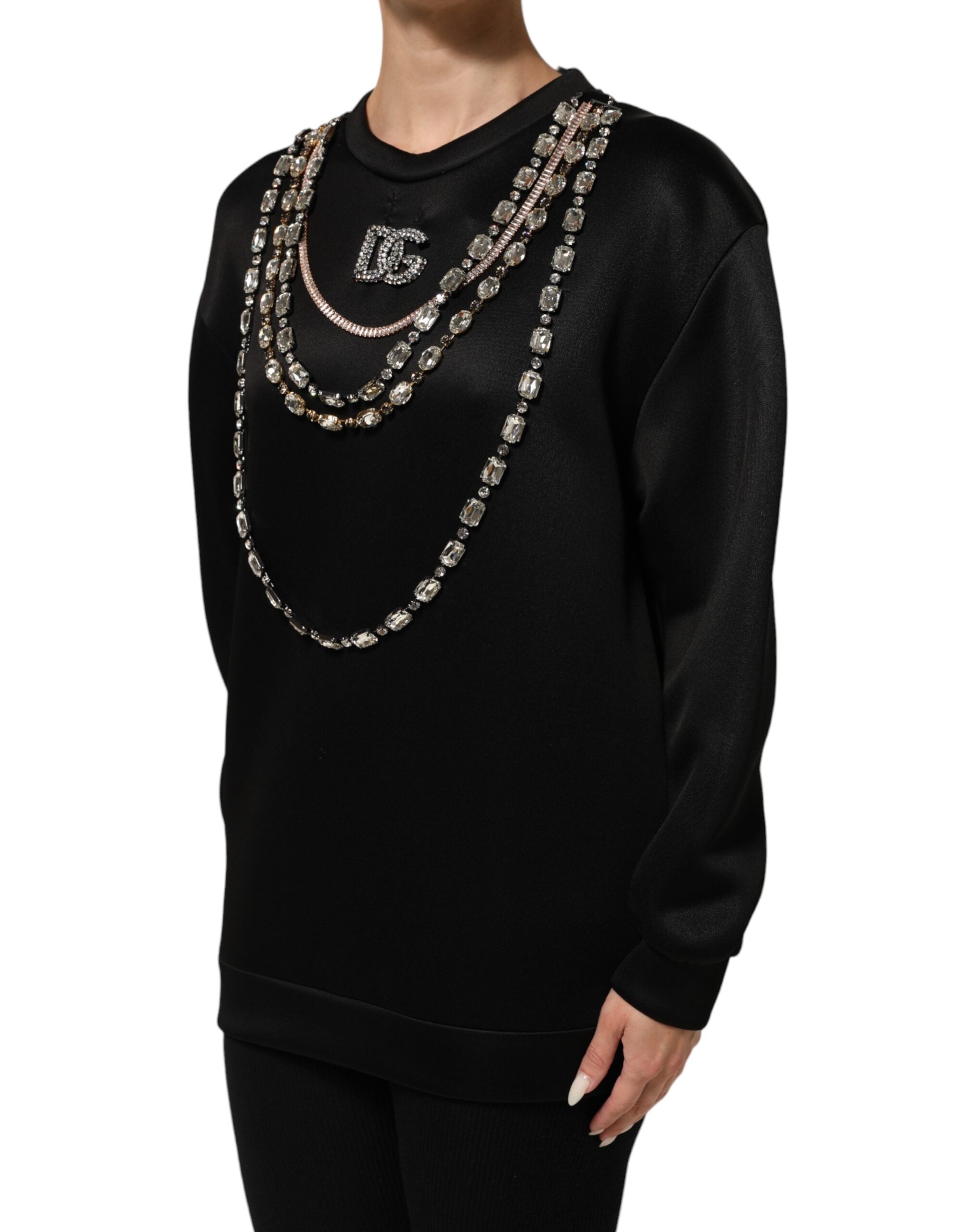 Pull à col rond noir Dolce & Gabbana avec logo en cristaux et collier assorti visible sur le sweat-shirt.