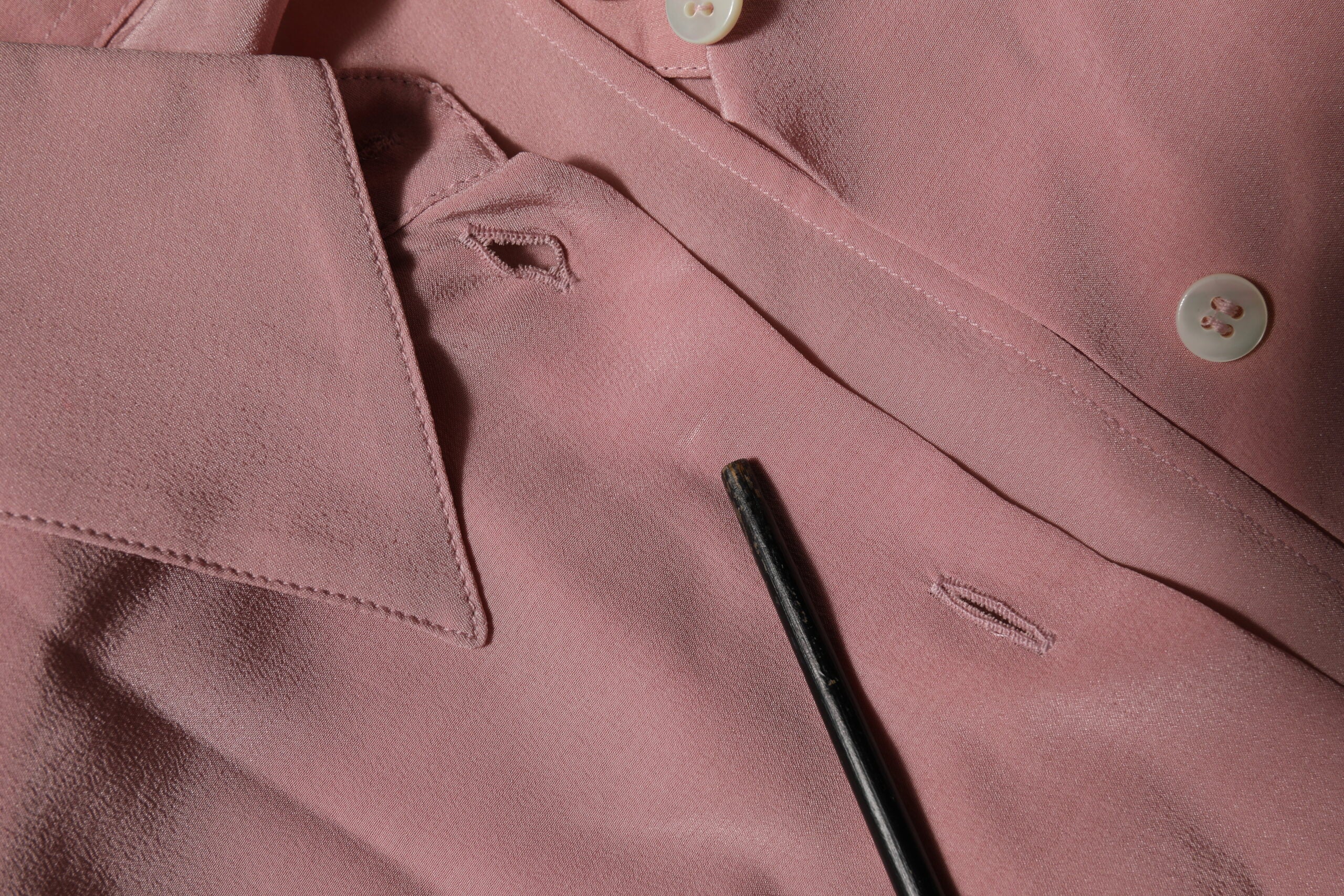 Chemisier en soie rose Dolce & Gabbana à col et manches longues, élégant et sophistiqué, visible avec détails de couture.