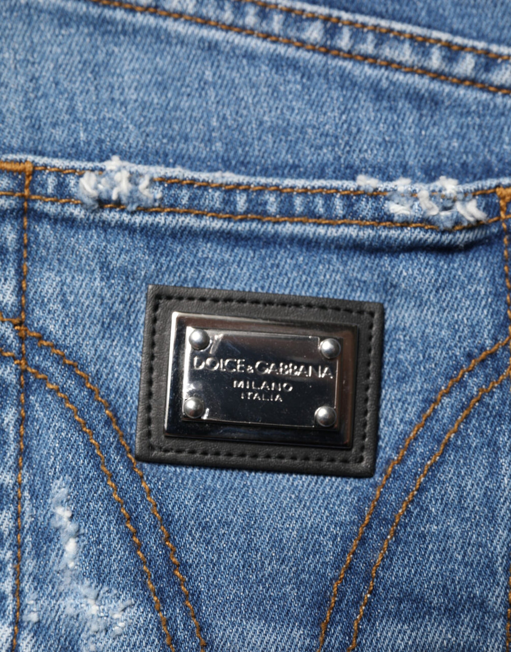 Jeans en denim bleu délavé et usé de Dolce & Gabbana, coupe décontractée avec détails déchirés.