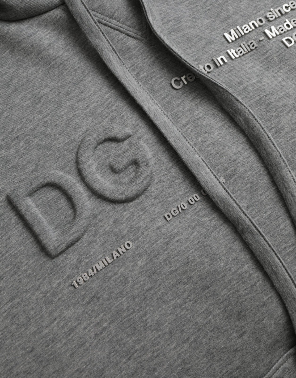 Sweat à capuche en coton gris Dolce & Gabbana avec logo, style décontracté, porté sur un mannequin.