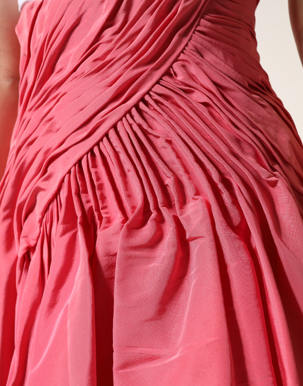 Jupe midi plissée en soie rose Dolce & Gabbana à taille haute, visible en détail dans l'image.