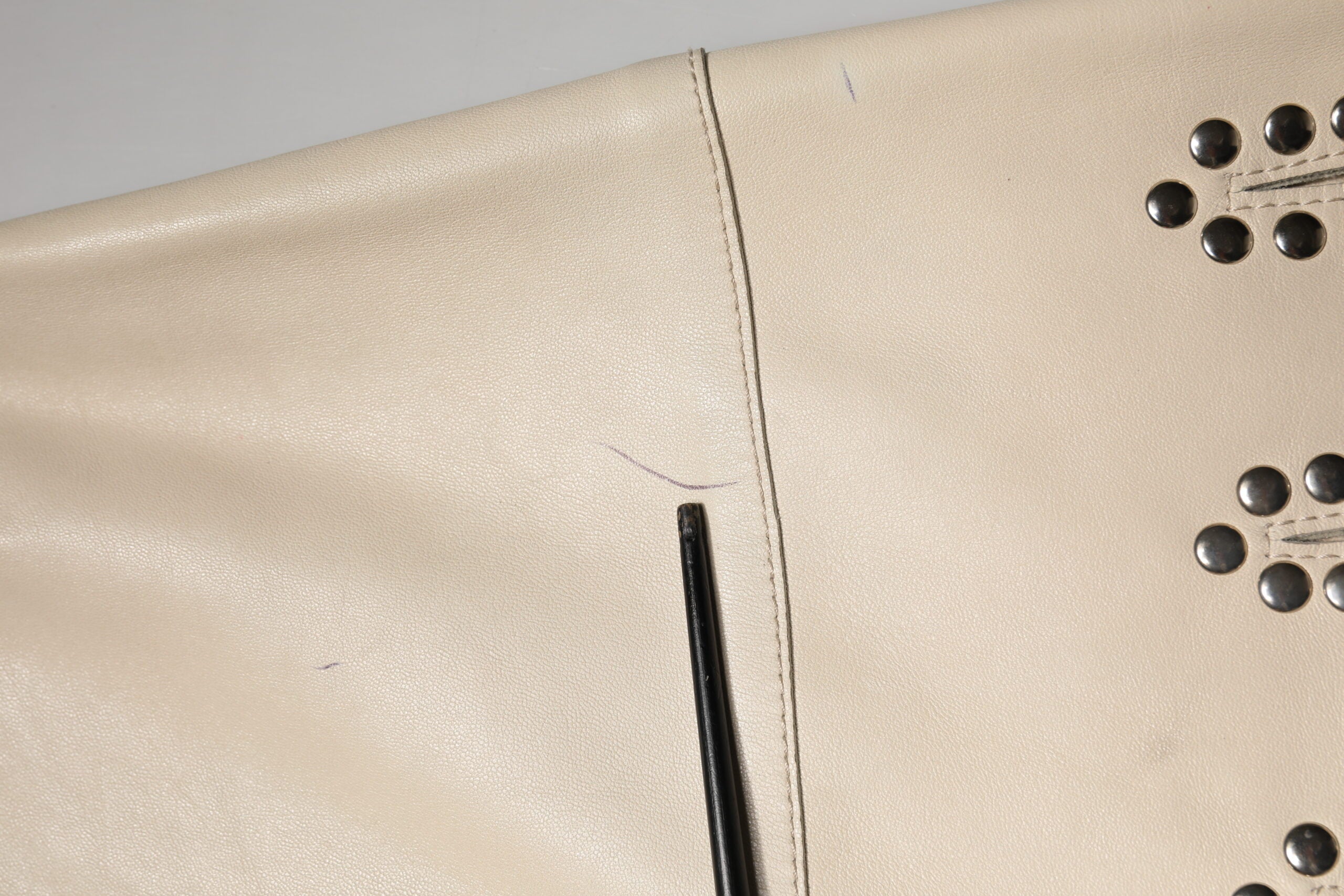 Jupe courte beige en cuir avec studs de marque Dolce & Gabbana, taille mi-haute, vue de face sur fond neutre.