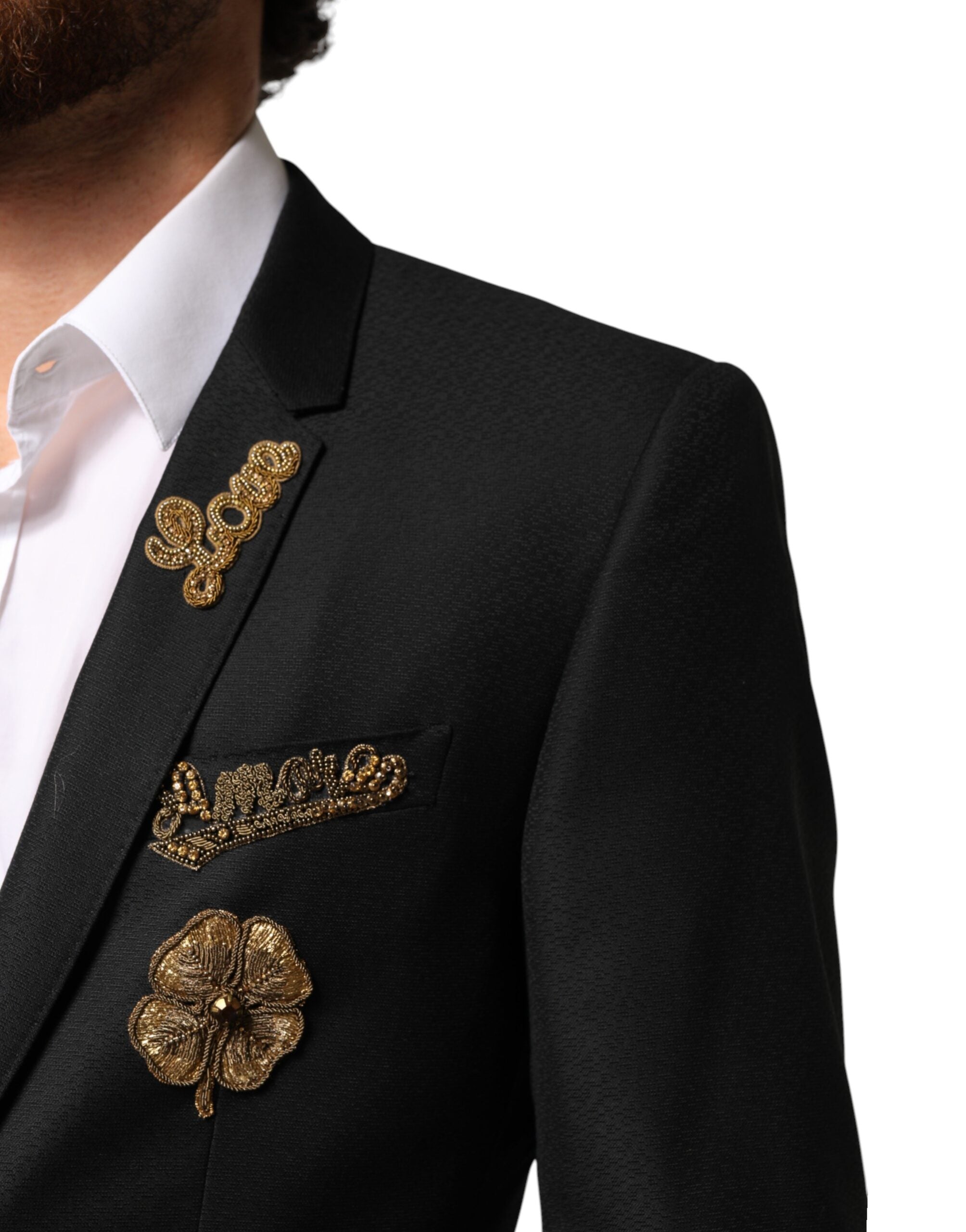 Costume deux pièces Dolce & Gabbana noir à boutons, avec embellissements et coupe croisée, porté sur un mannequin.
