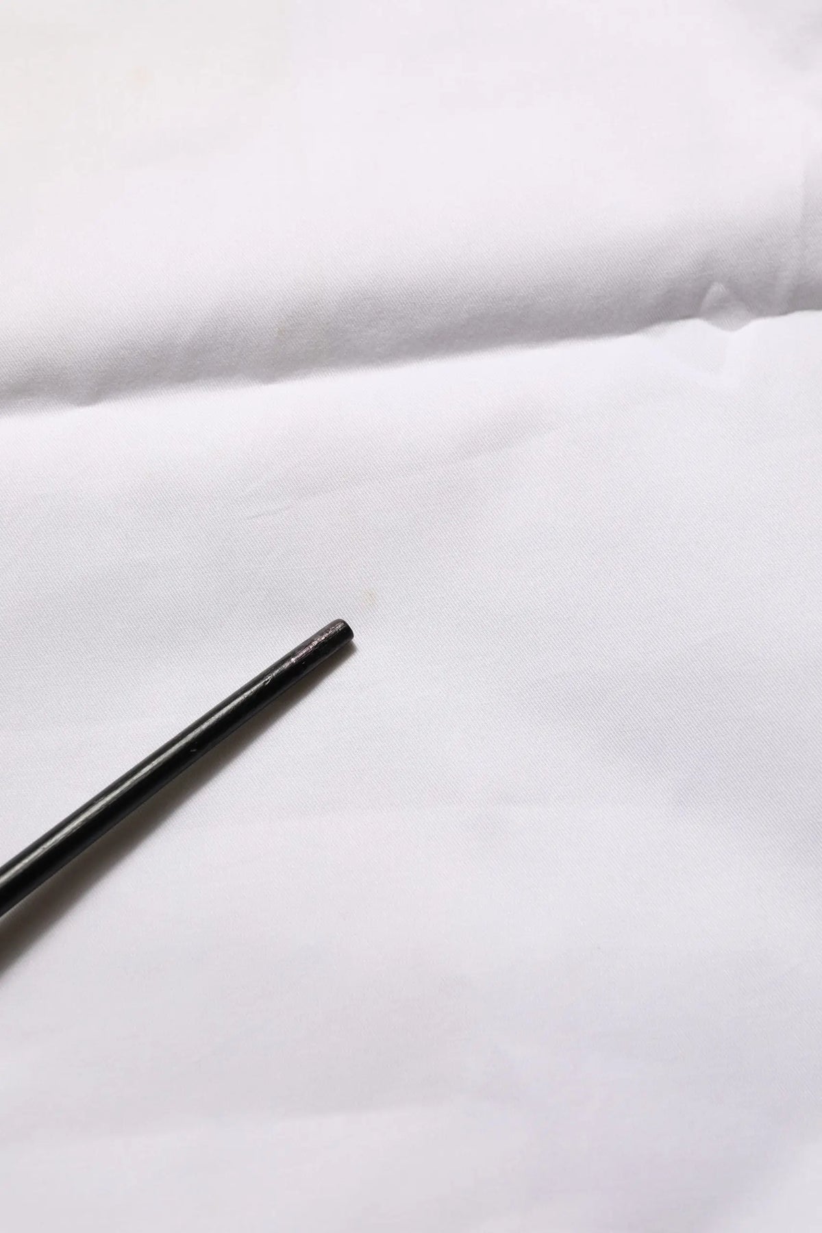 Black chopsticks resting on a white surface next to armani jeans white mid waist cotton stretch trouser pants