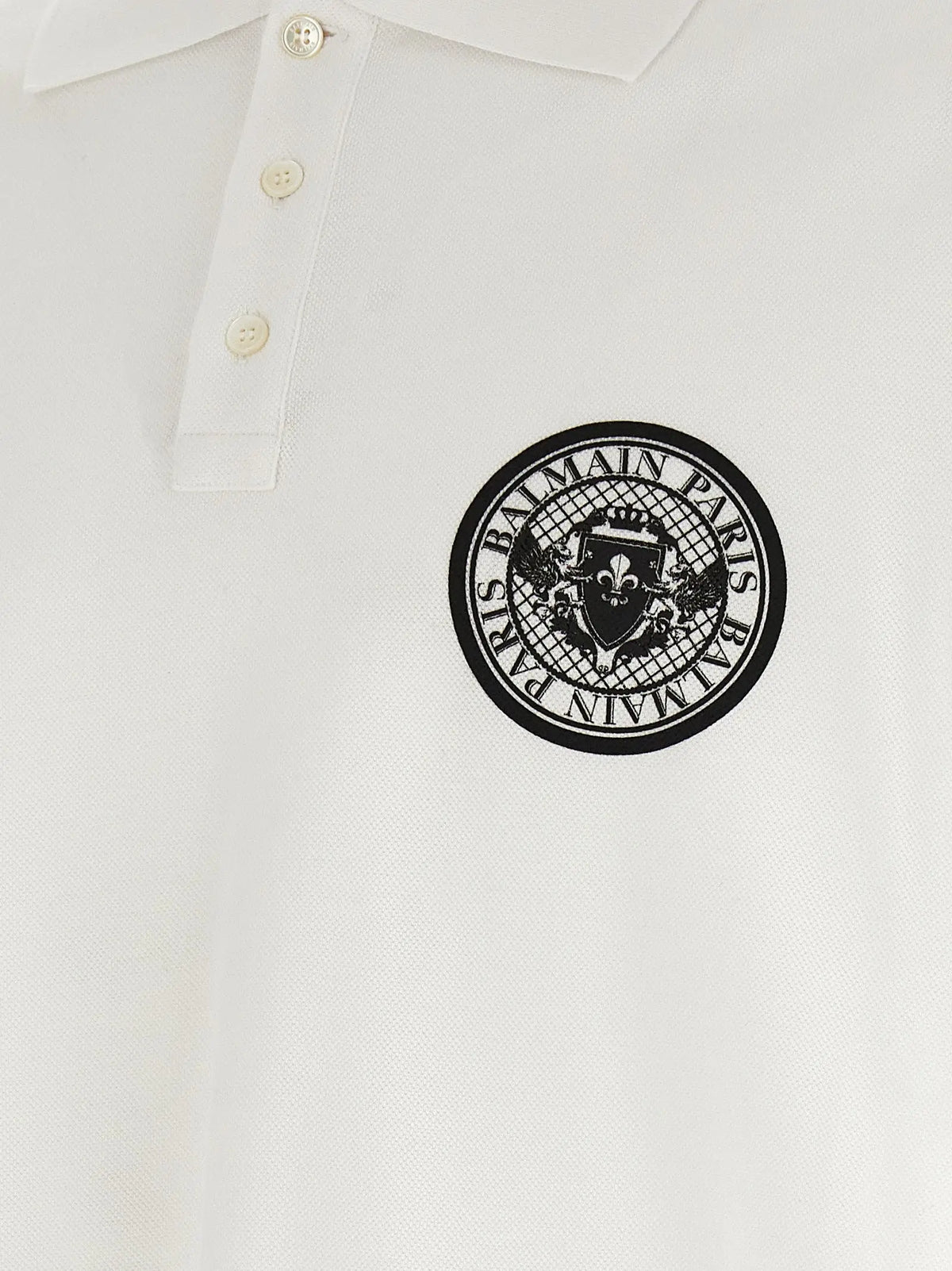 White balmain paris polo shirt in cotton featuring a black circular logo with brand name and crest embroidered on the chest