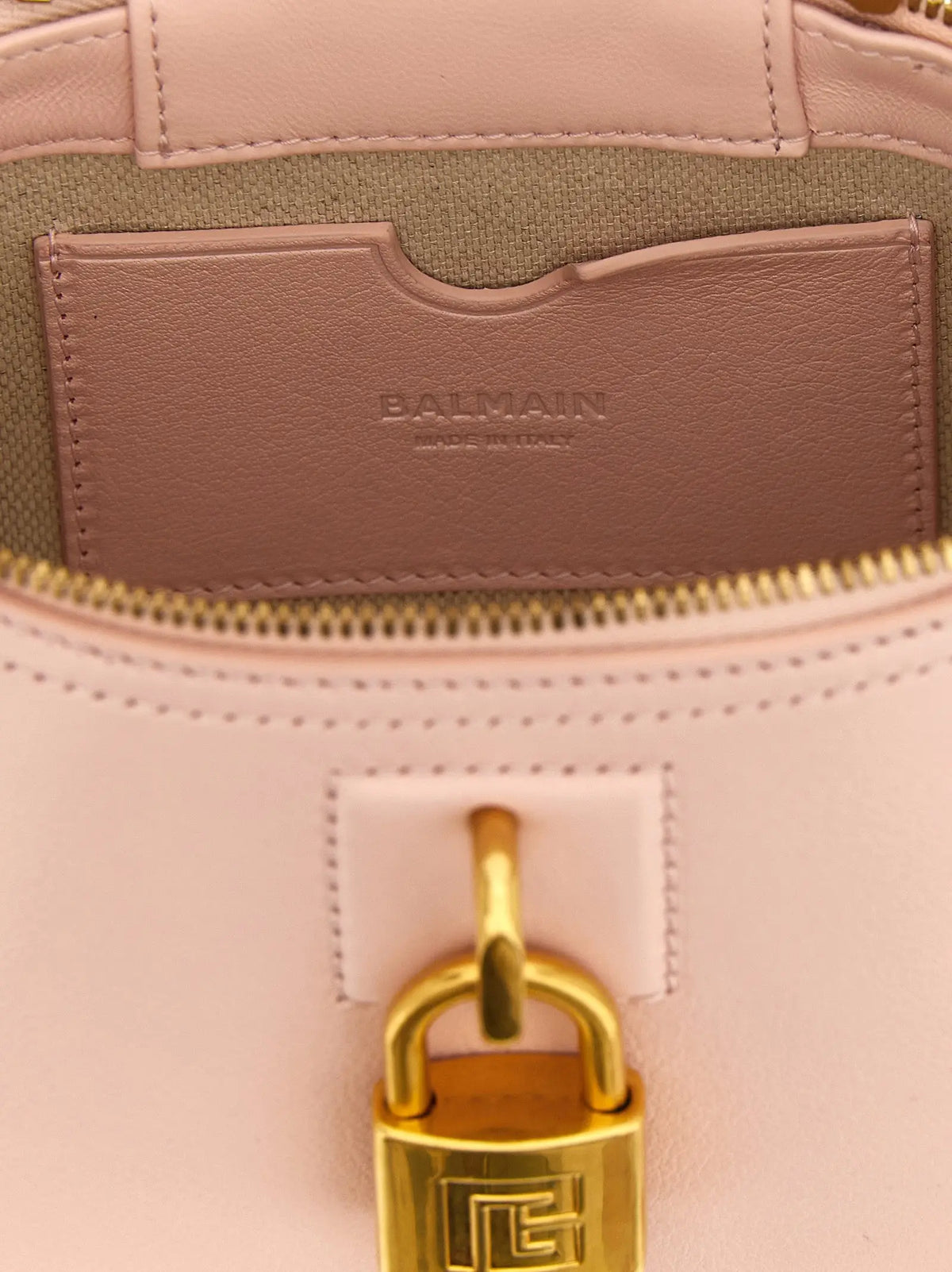 Un sac à main balmain multicolore en cuir de veau rose avec fermeture cadenas dorée et logo embossé
