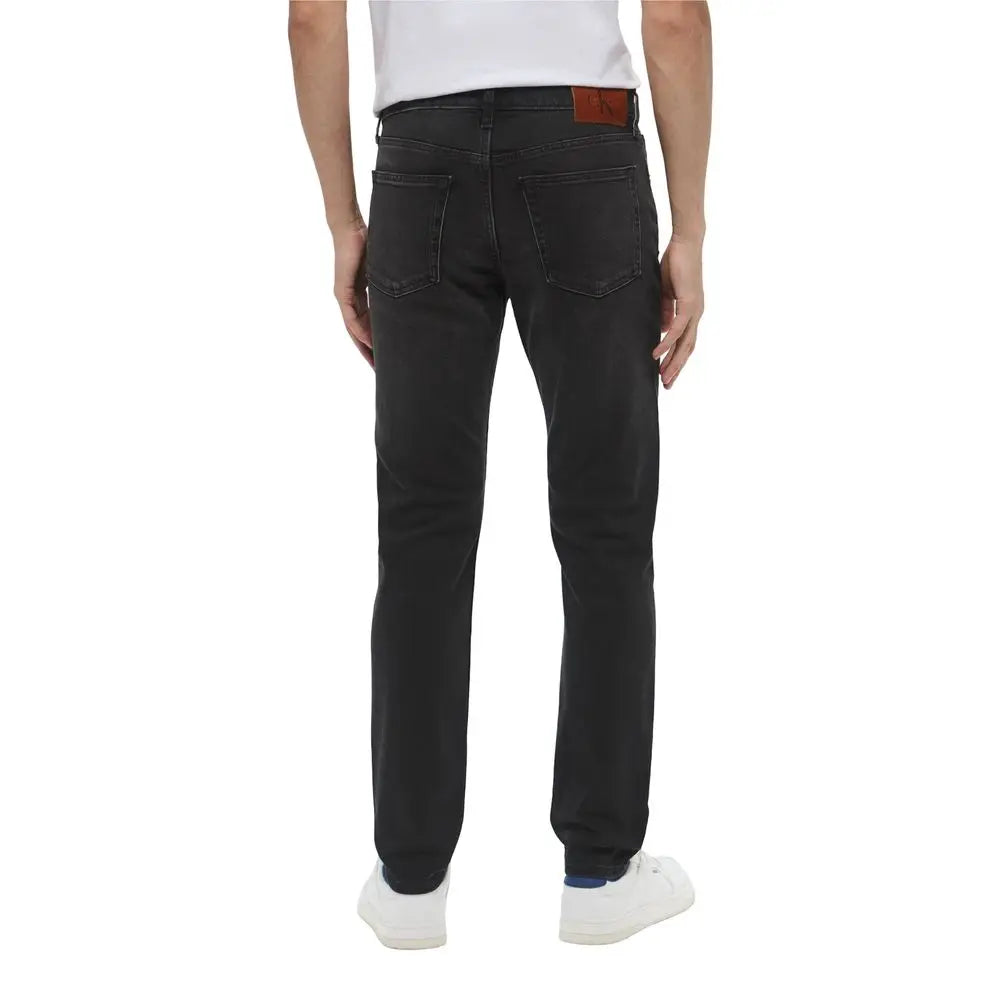 Jeans noirs en denim Calvin Klein slim en coton avec patch en cuir marron visible à l’arrière sur la ceinture