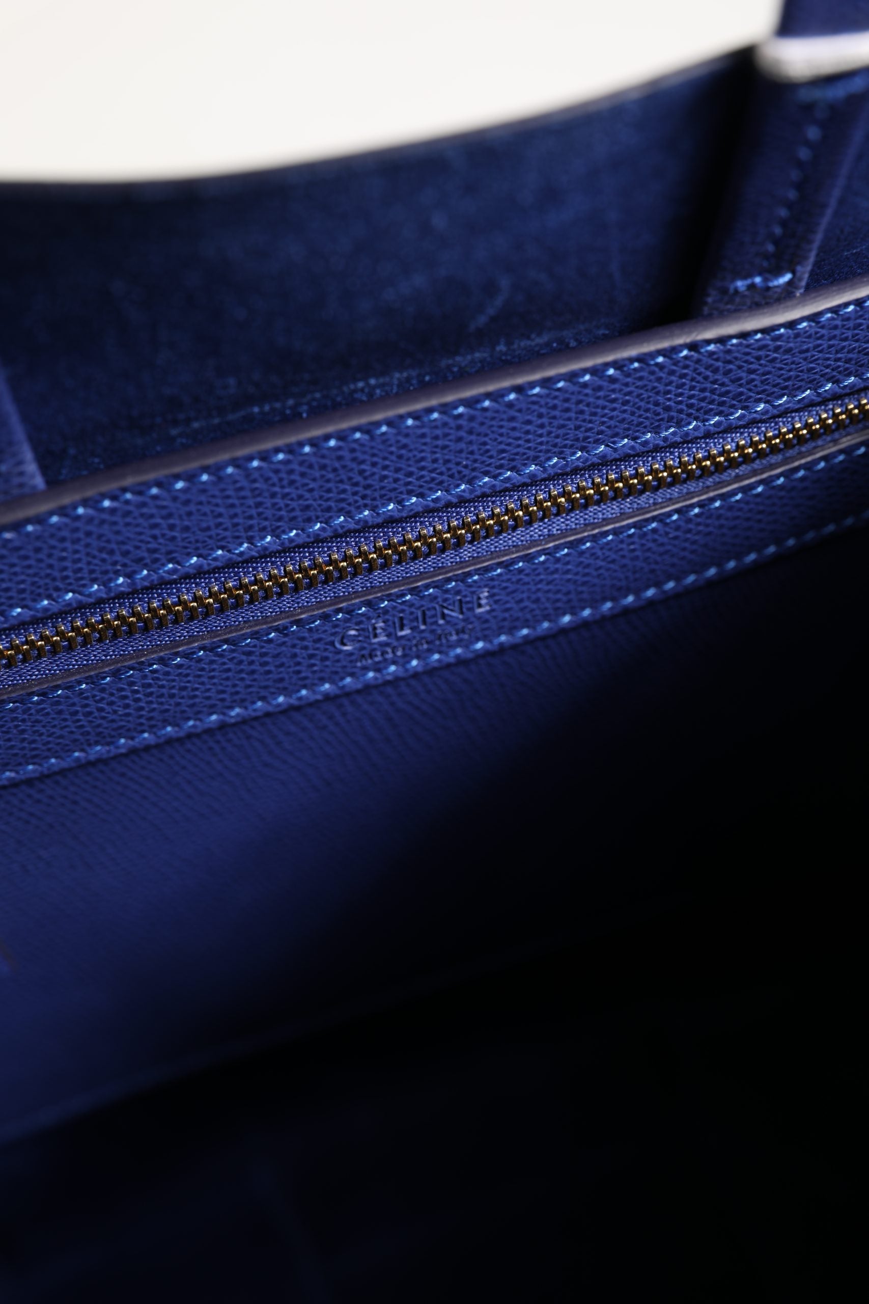 Sac cabas Celine bleu avec détails dorés, en cuir élégant, porté avec des poignées épaisses et un design sophistiqué.