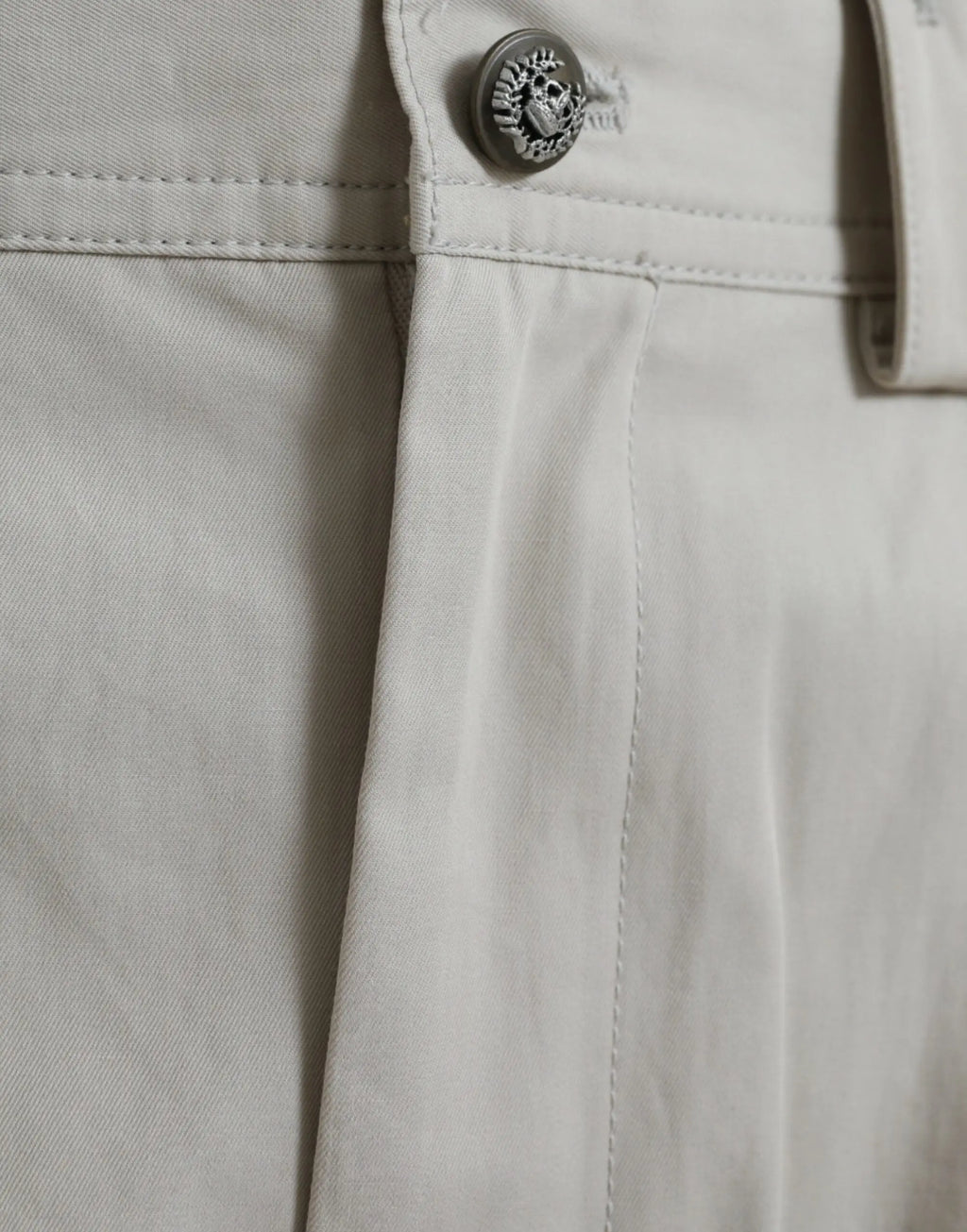 Bouton en forme de crâne argenté détaillé sur la taille du pantalon beige en coton dolce gabbana à taille haute