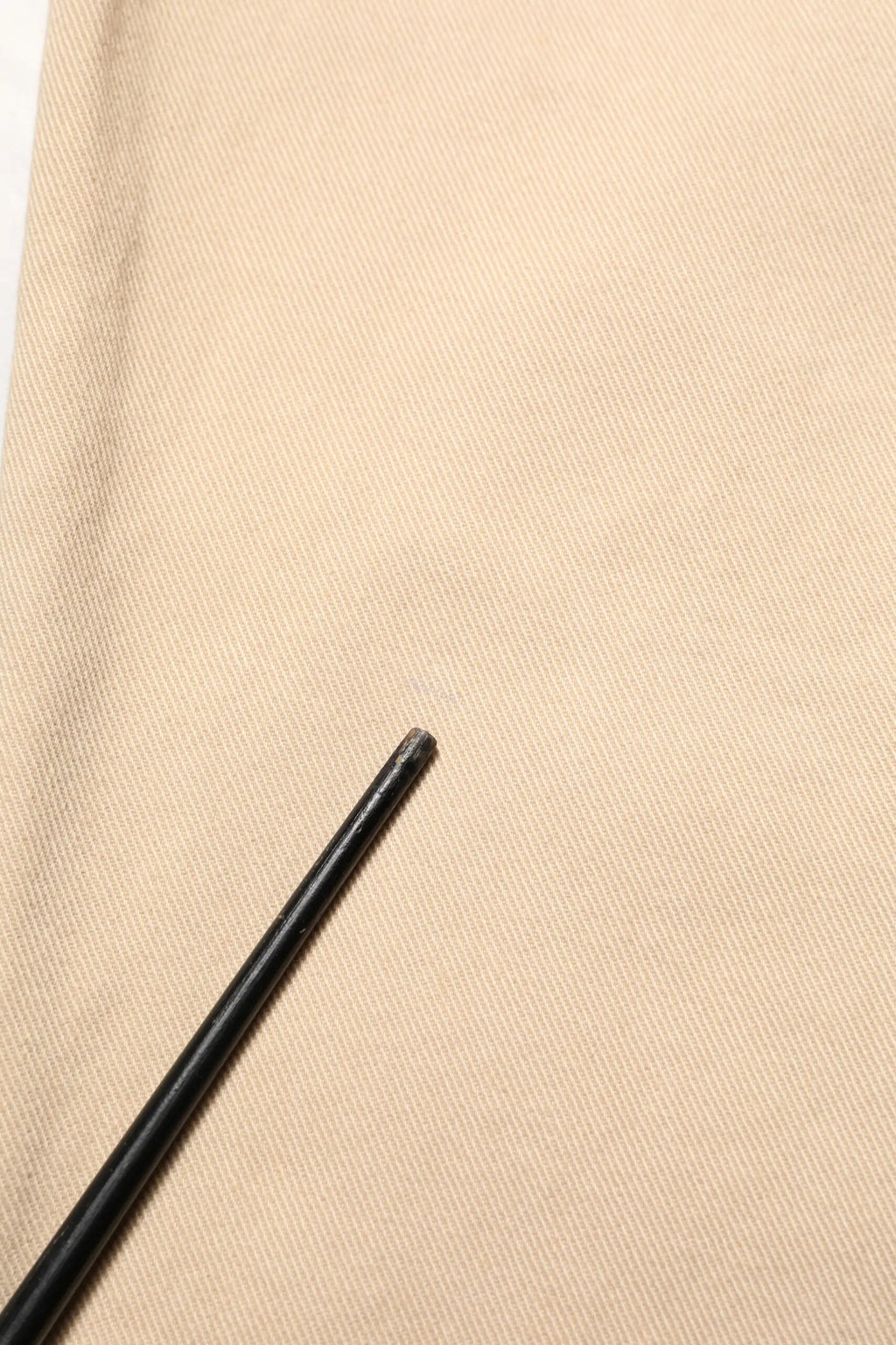 Crayon noir à pointe légèrement usée posé sur tissu beige comme fond pour jean homme beige en coton dolce & gabbana
