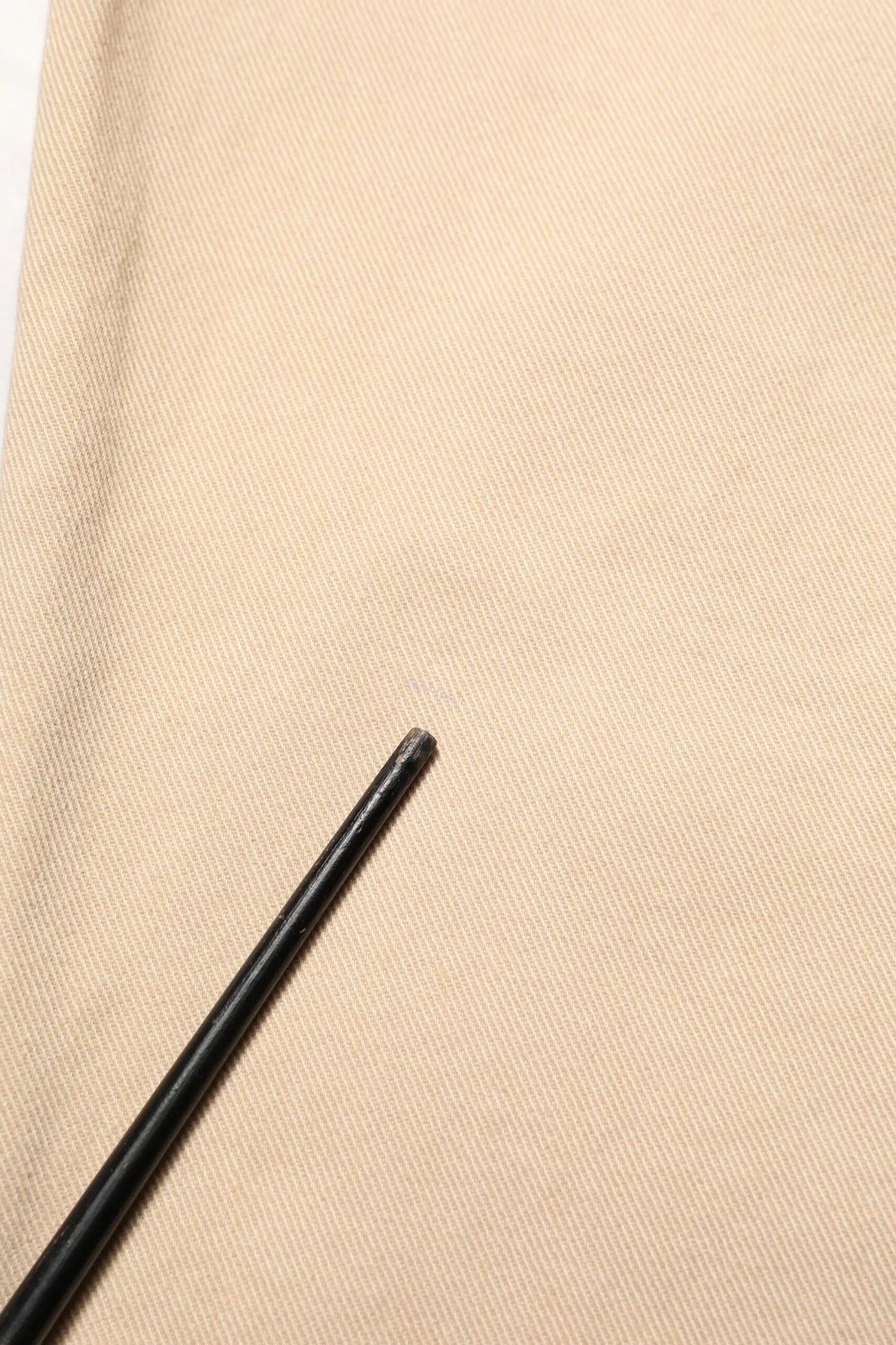 Crayon noir à pointe légèrement usée posé sur tissu beige comme fond pour jean homme beige en coton dolce & gabbana