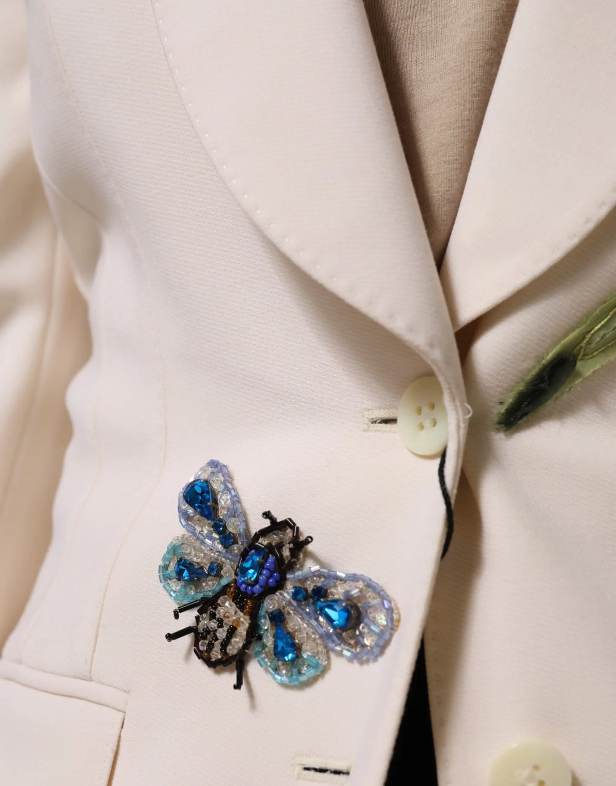 Broche scarabée bleue et argentée à perles brillante sur veste beige brodée dolce gabbana simple boutonnage