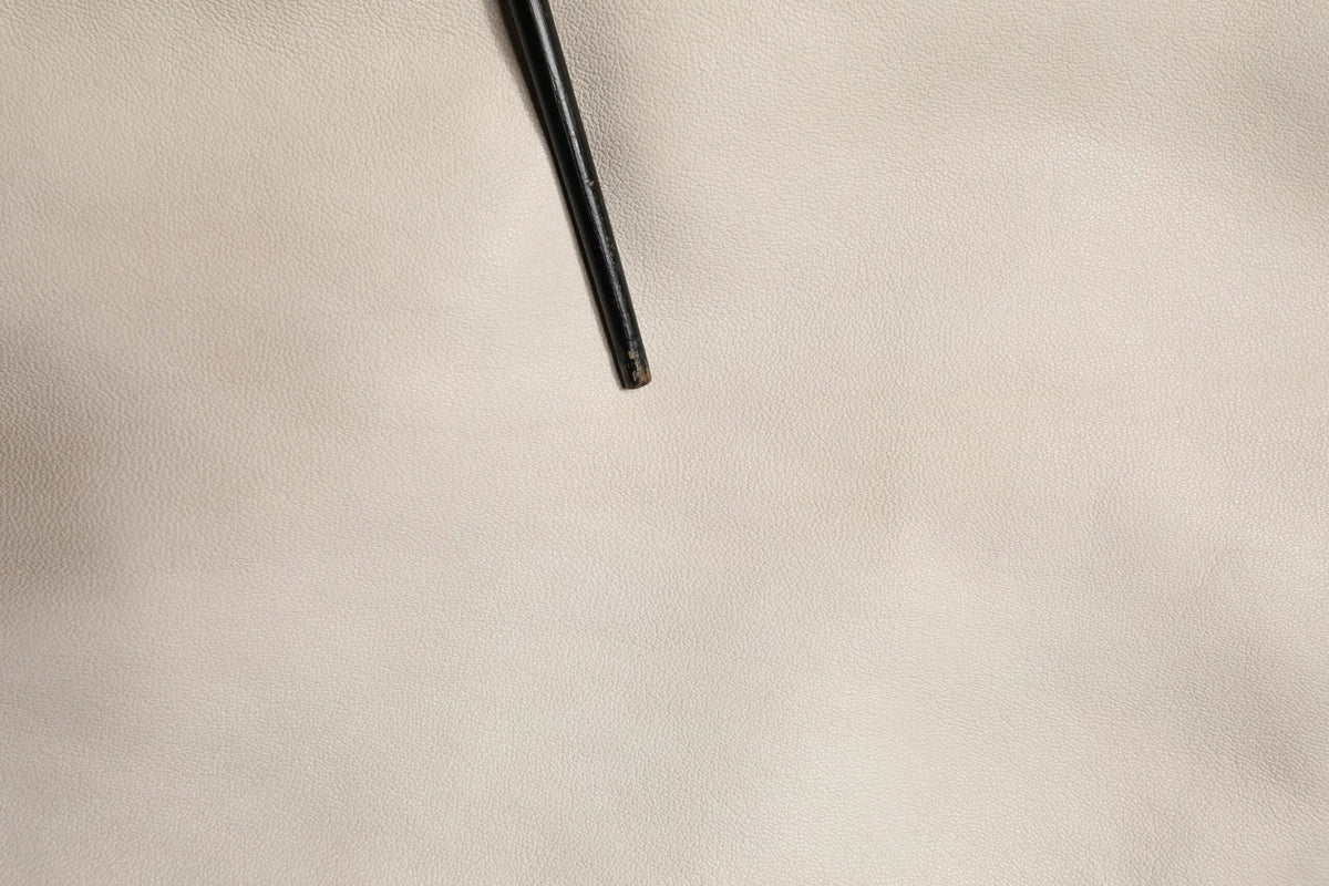 Black metal baguette reposant sur une surface en cuir beige texturé du chemise décontractée pour homme dolce & gabbana