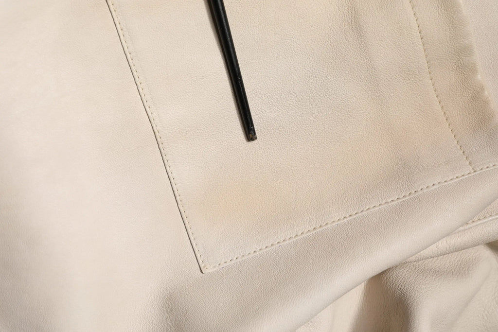 Un stylo noir élégant posé en diagonale sur une poche en cuir beige doux avec couture précise sur une chemise homme casual dolce & gabbana