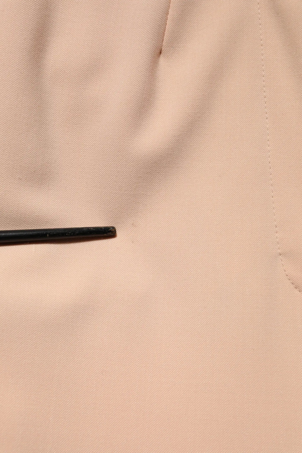 Un stylo noir mince posé sur un tissu pêche douce avec un pantalon beige en polyester dolce & gabbana taille moyenne tapered