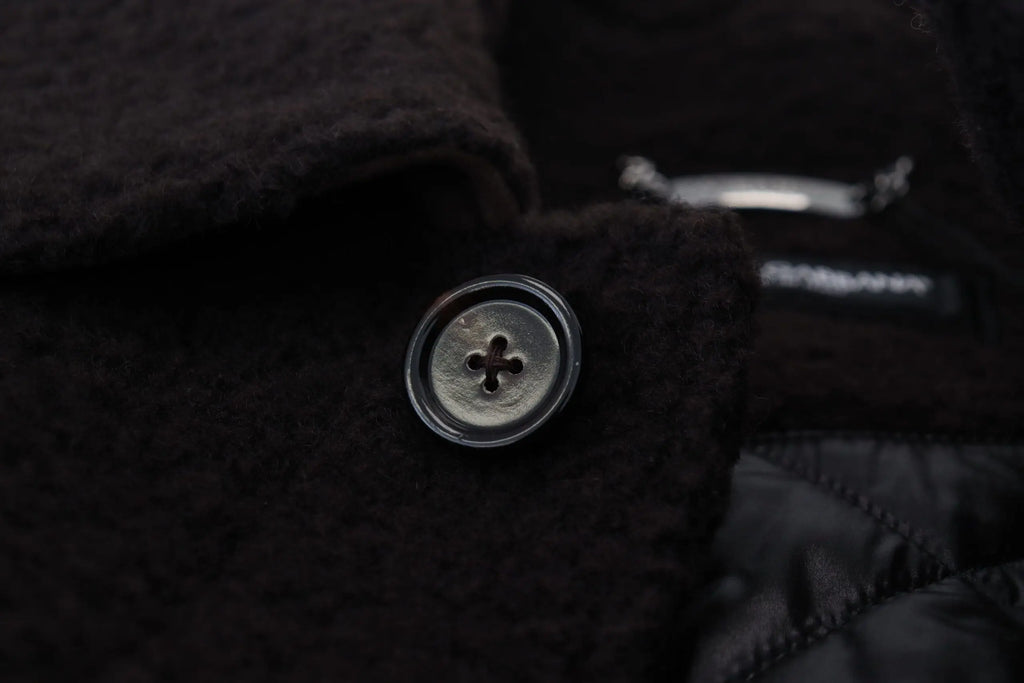 Bouton rond argenté avec une indentation en croix sur tissu brun foncé pour trench coat dolce gabbana en alpaga noir