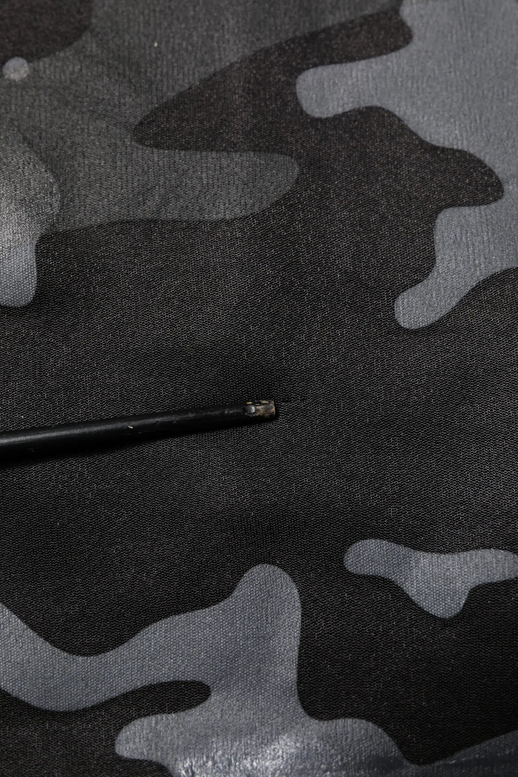 Objet cylindrique noir avec extrémité métallique sur tissu camouflage gris et noir du pullover dolce & gabbana