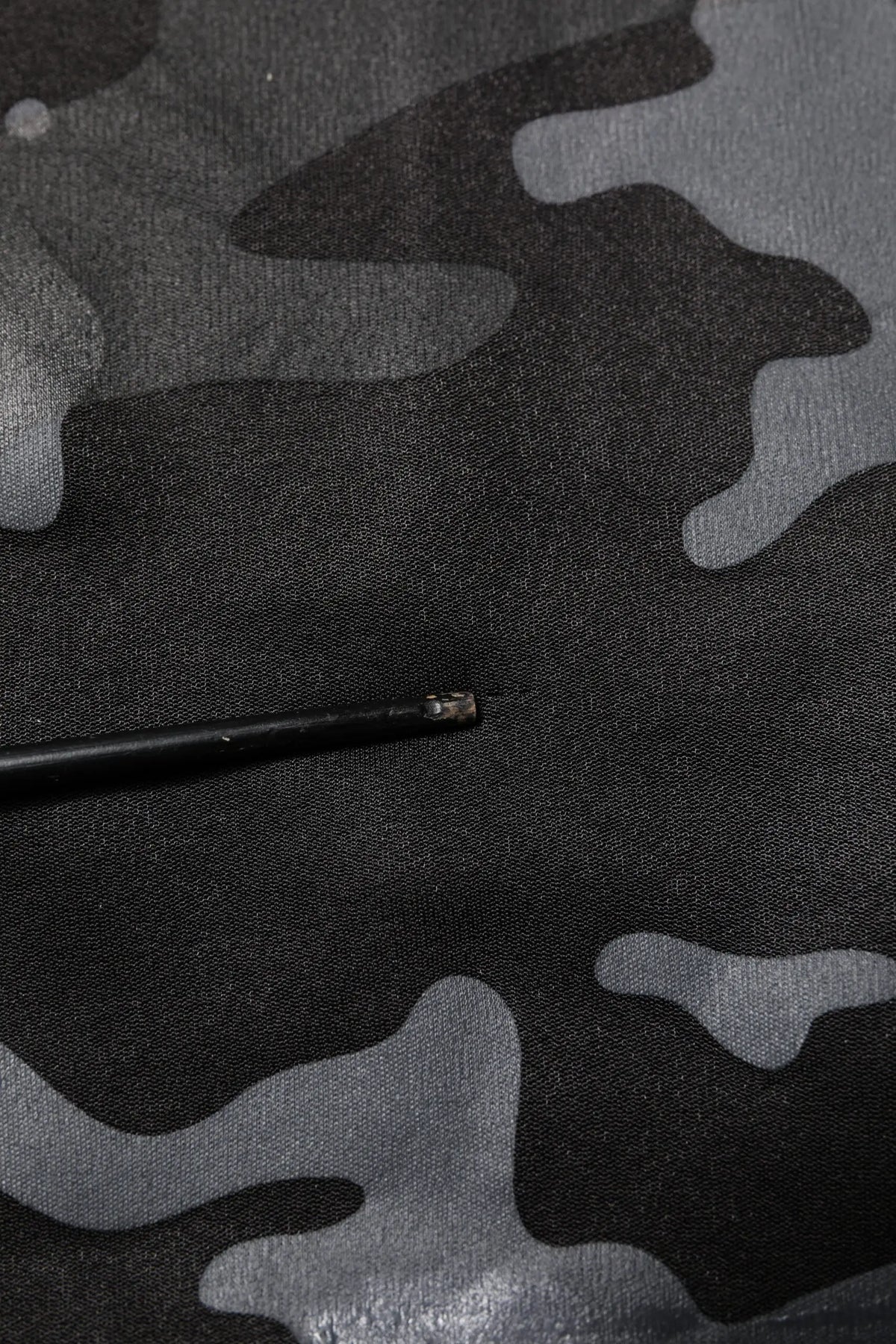 Objet cylindrique noir avec extrémité métallique sur tissu camouflage gris et noir du pullover dolce & gabbana
