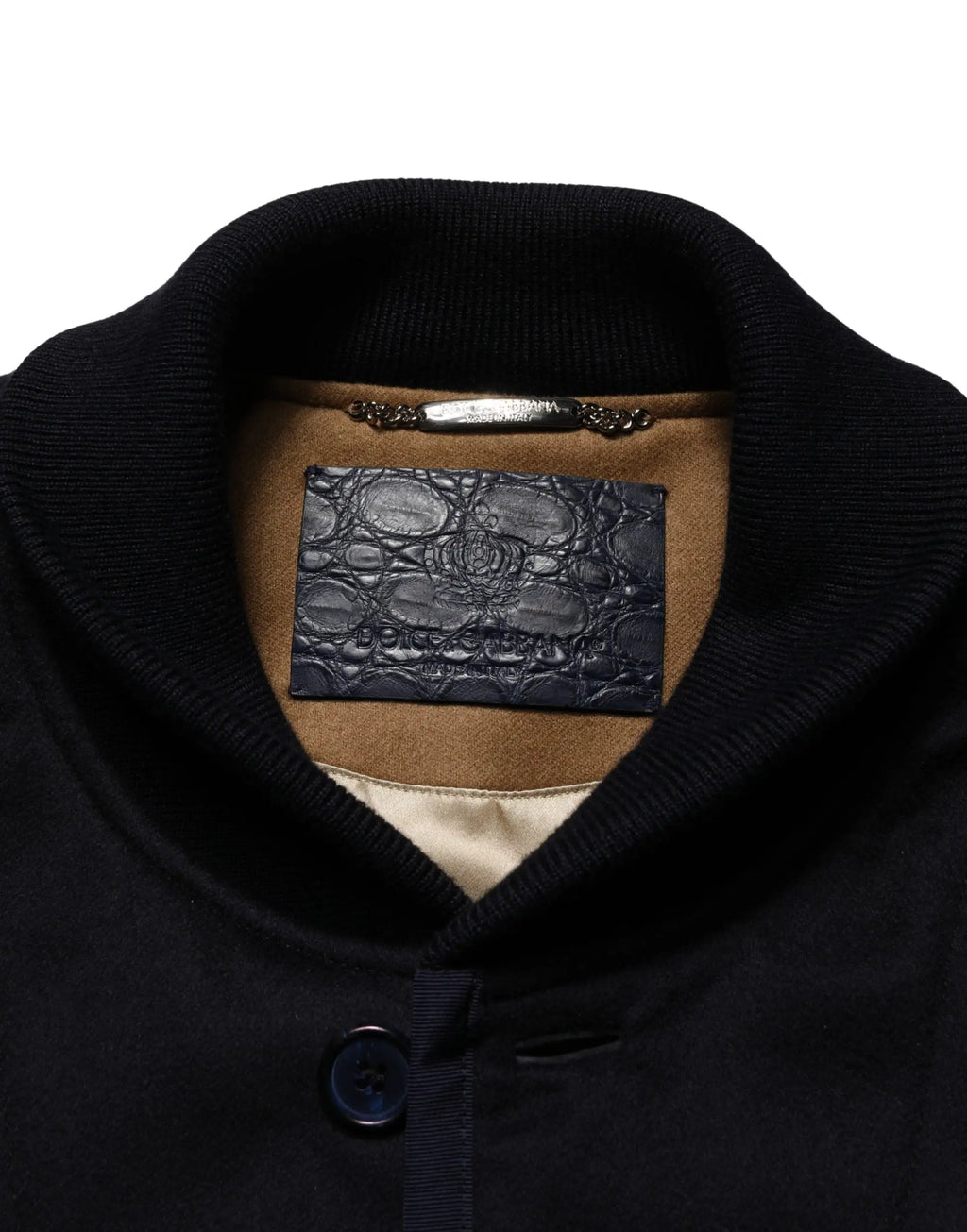Étiquette en cuir embossé crocodile bleu foncé dolce & gabbana avec logo doré sur doublure en daim beige d’une veste noire en cachemire côtelée