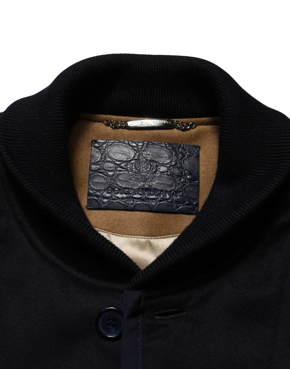 Étiquette en cuir embossé crocodile bleu foncé dolce & gabbana avec logo doré sur doublure en daim beige d’une veste noire en cachemire côtelée